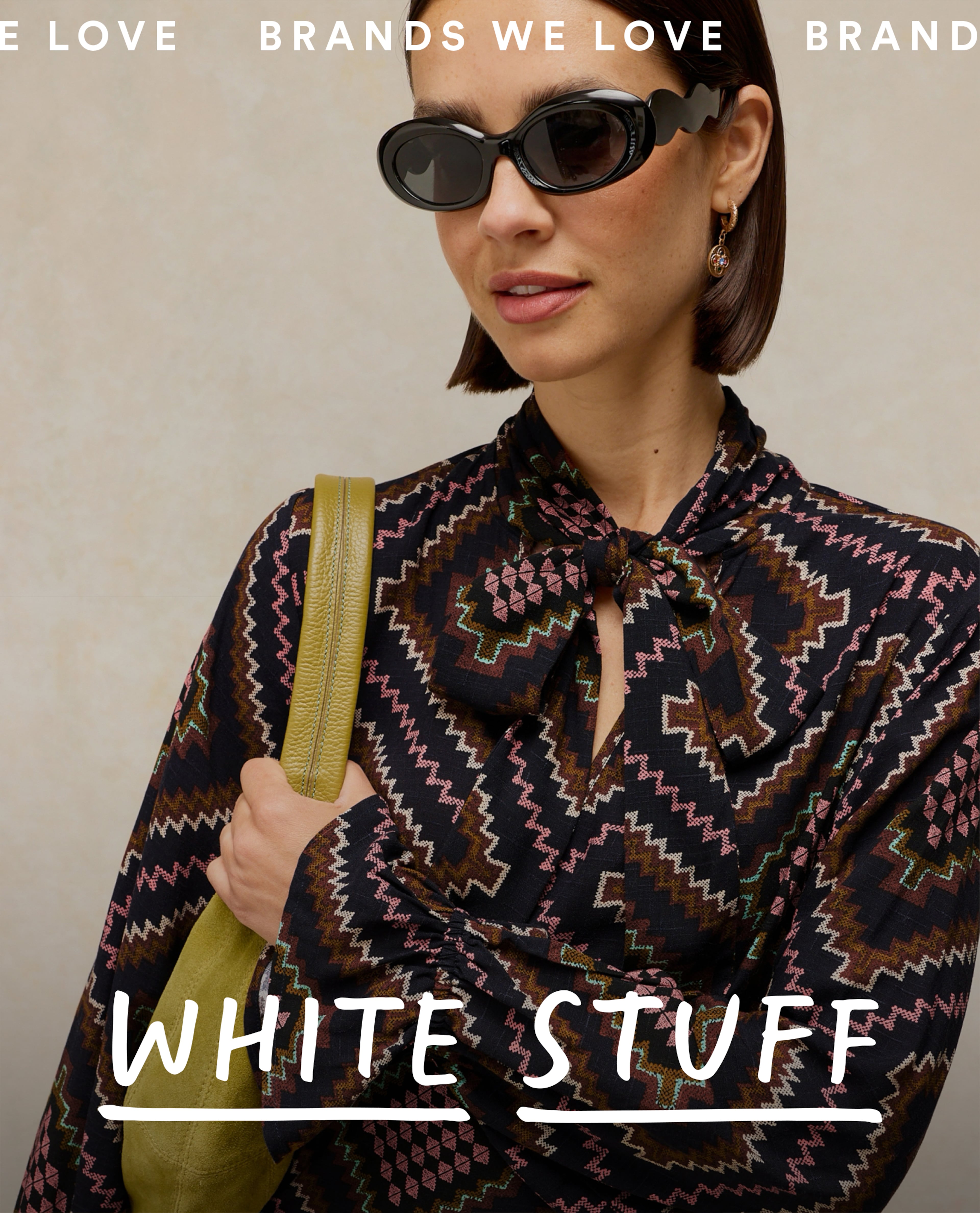 Model wears black print dress from White Stuff