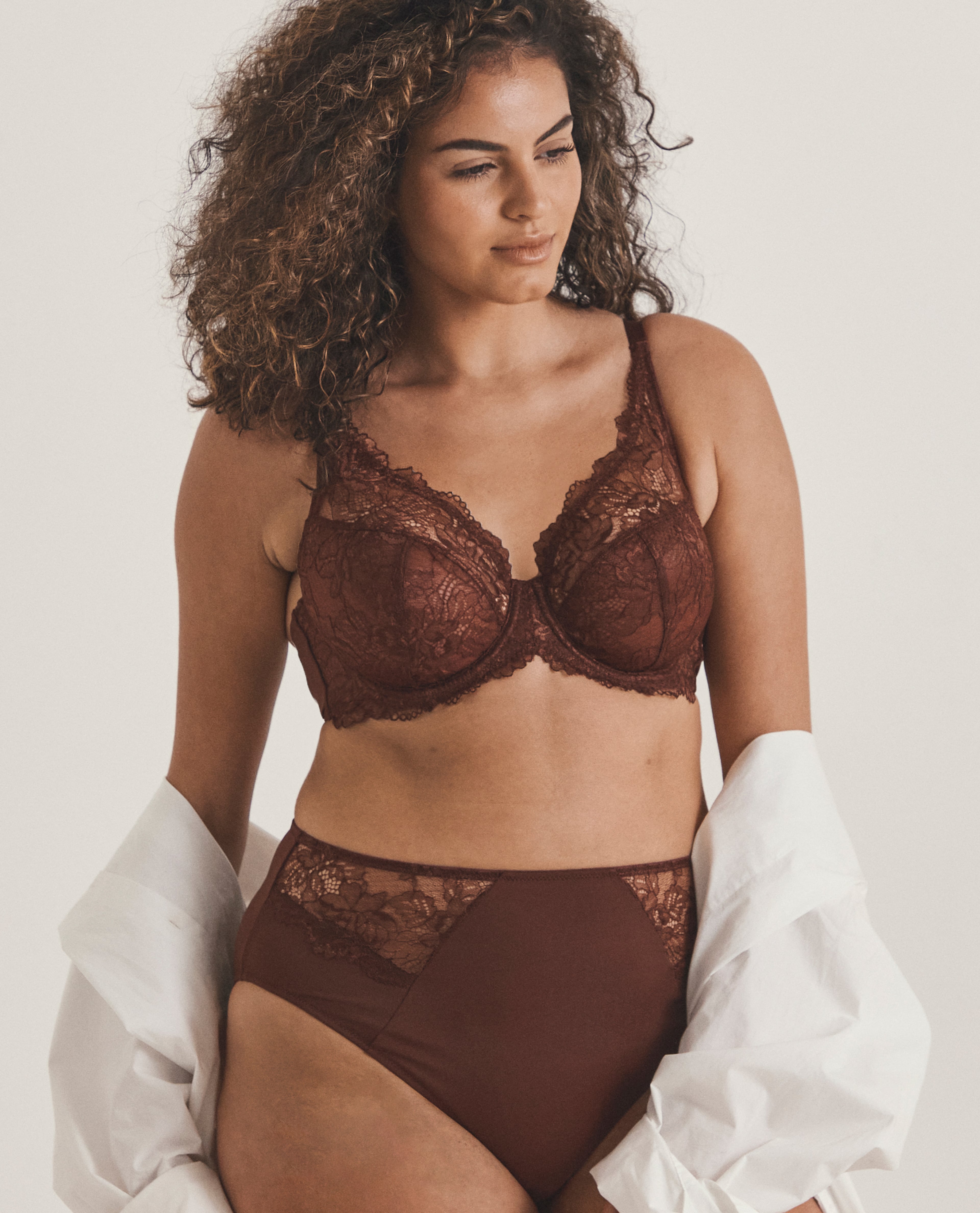 model wearing brown lingerie holding a white cardi