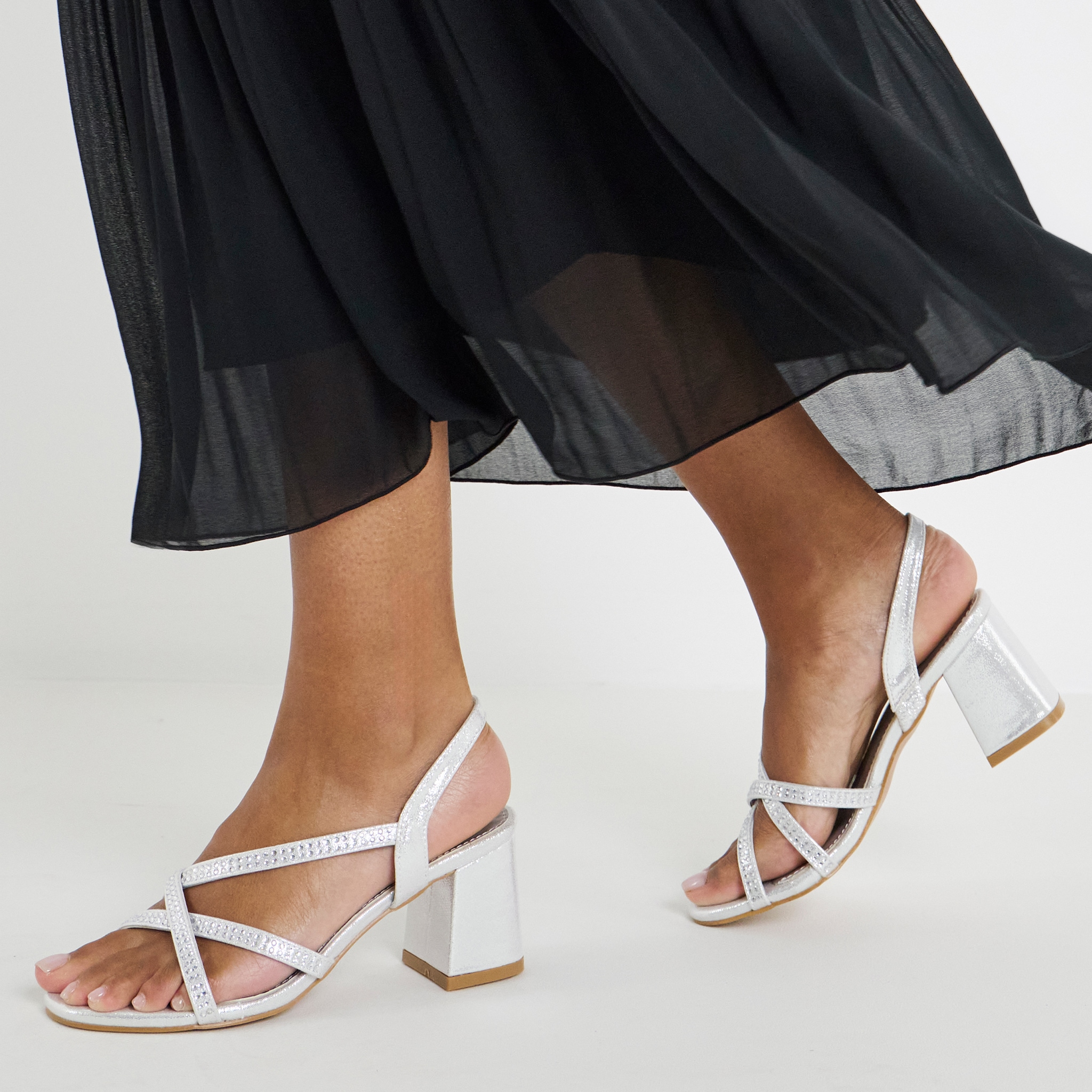 Model wearing black dress wearing white strap heald sandals