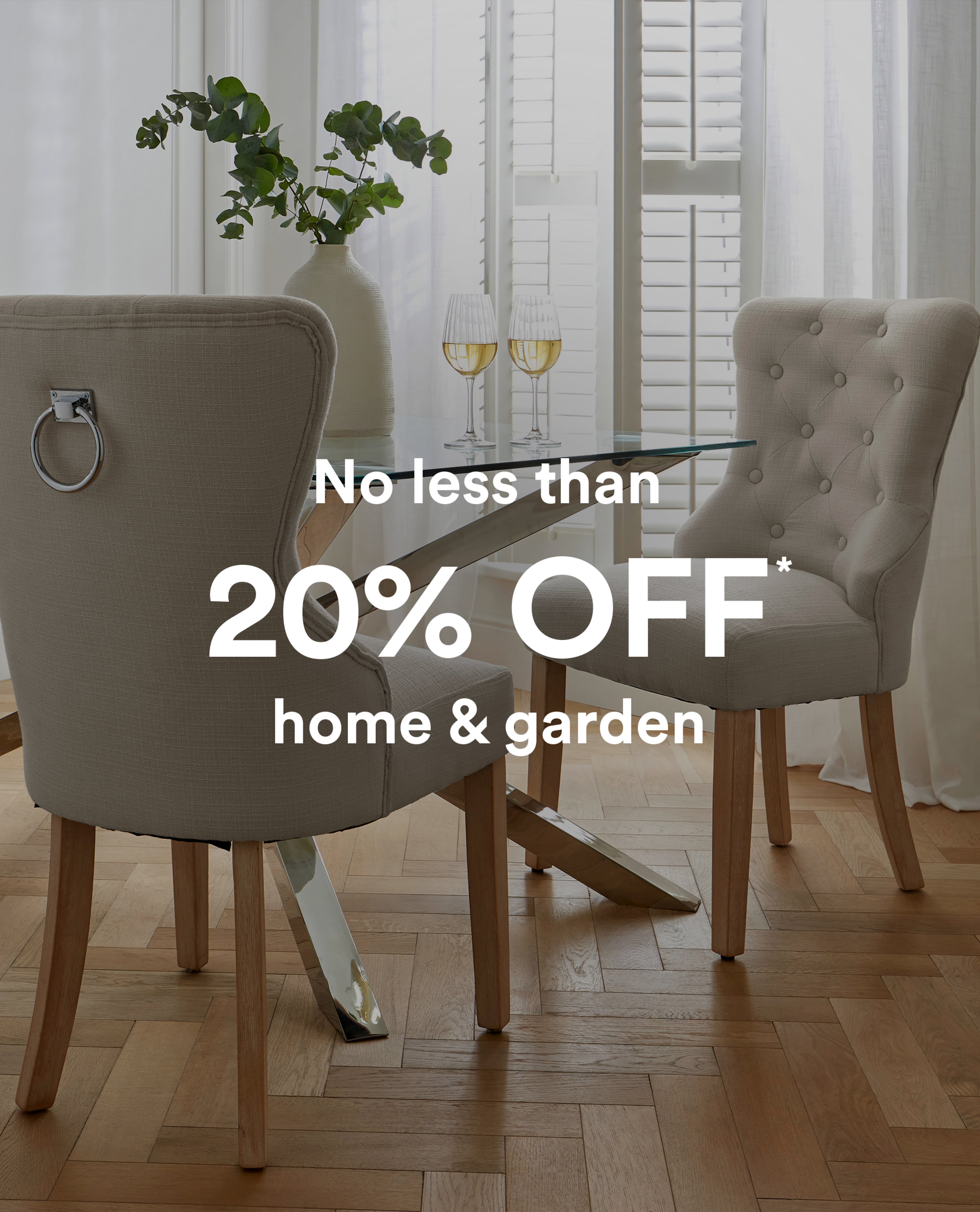 Dining area with upholstered chairs and a glass table set with two wine glasses, No less than 20% off home and garden.