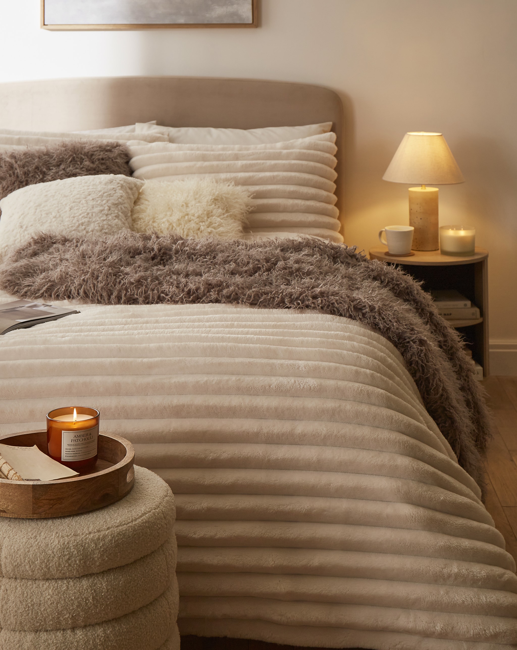 A bedroom with a bed dressed in thick fleece bedding and a brown throw.