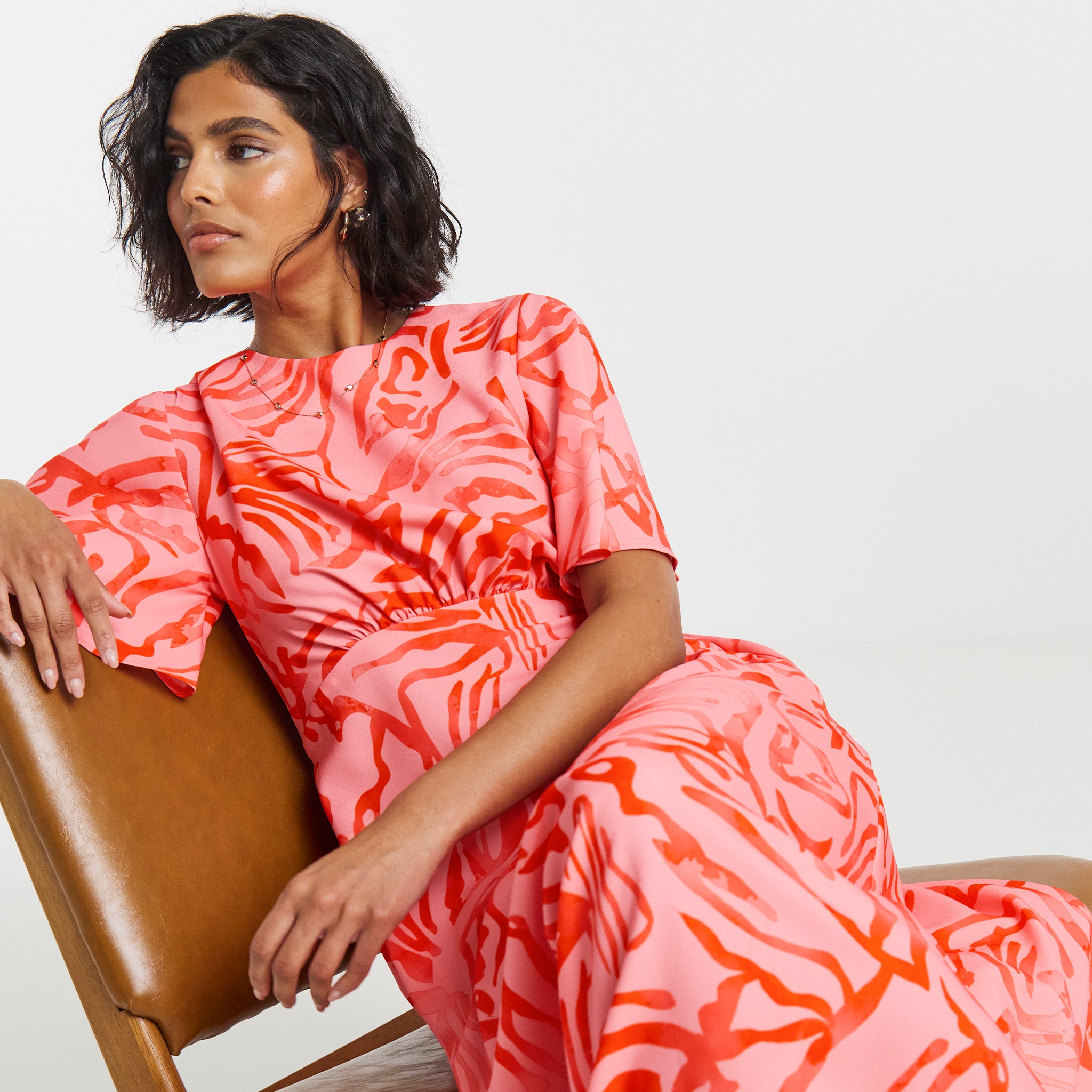 Modela weraing pink red dress sat on chair