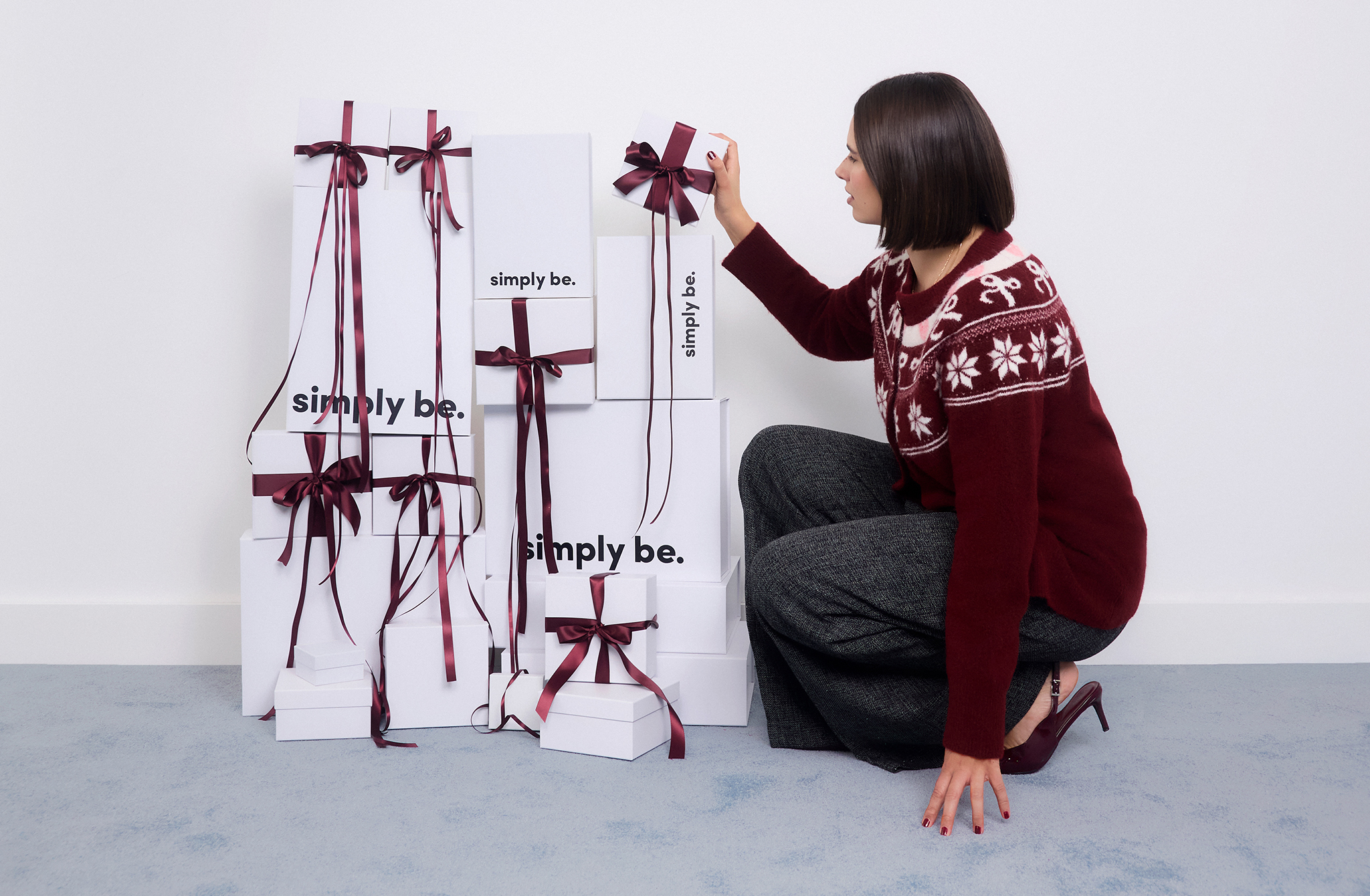 Model decorating boxes wears Brushed Yarn Burgundy Fair Isle Crew Neck Cardigan