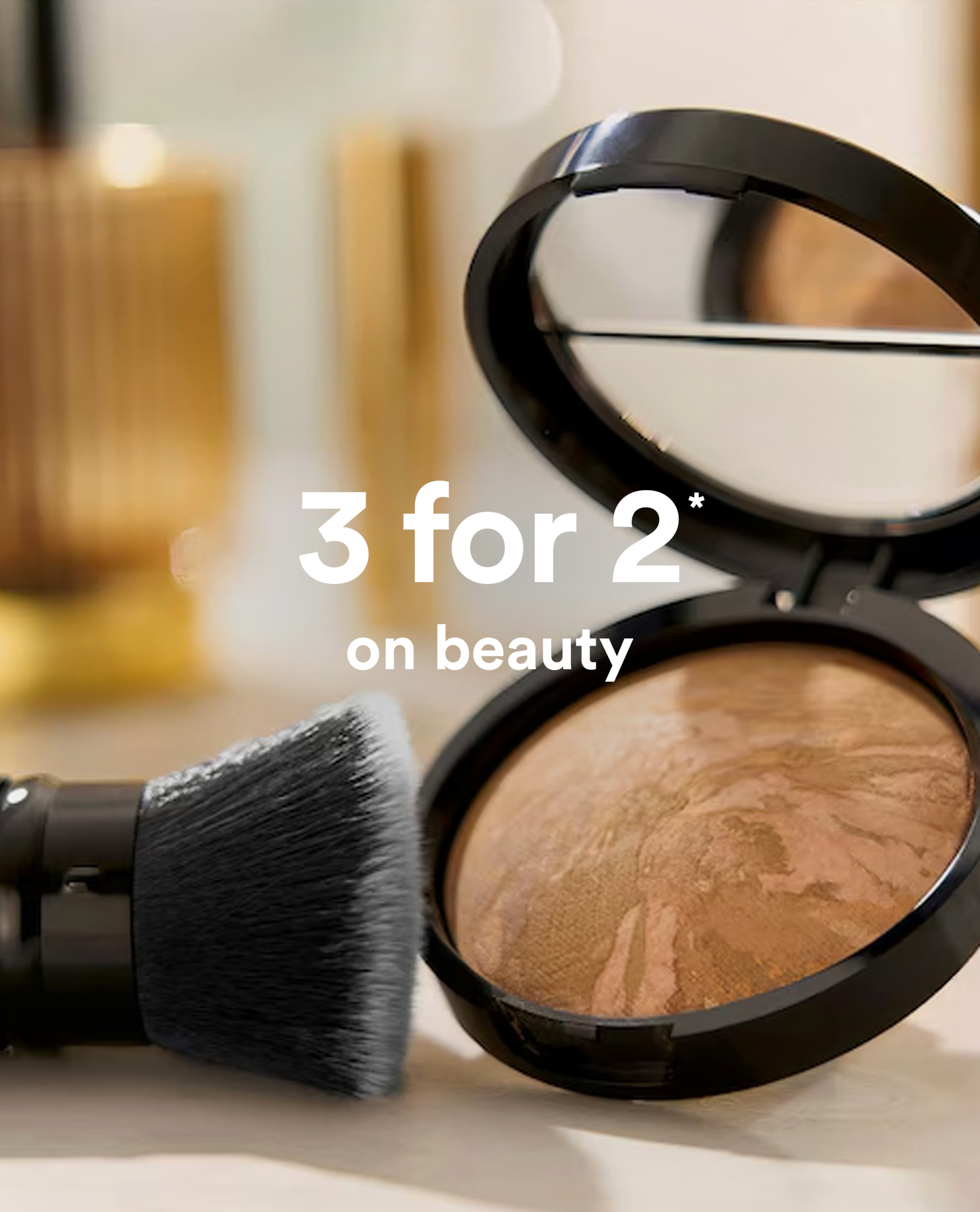 Close-up of bronzer compact and makeup brush with text 3 for 2 on beauty