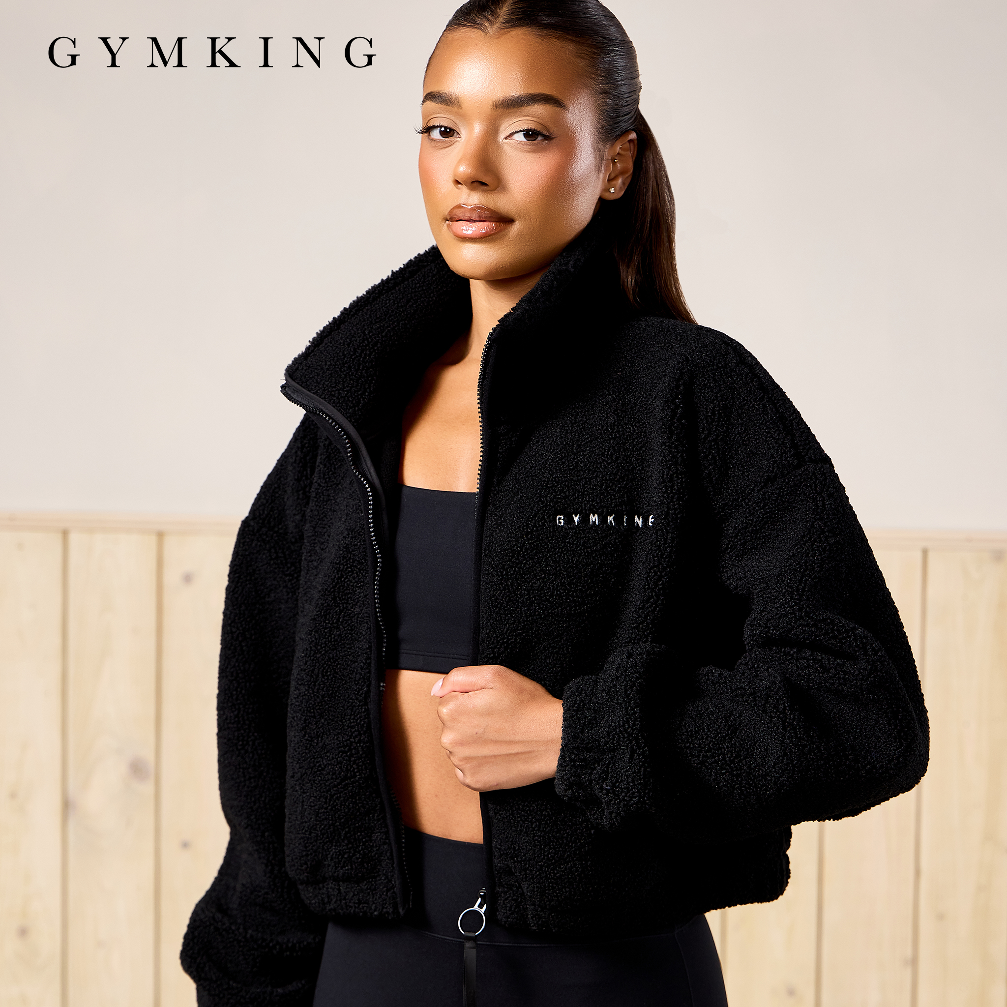 Model wears black fleece jacket and sports vest from Gym King