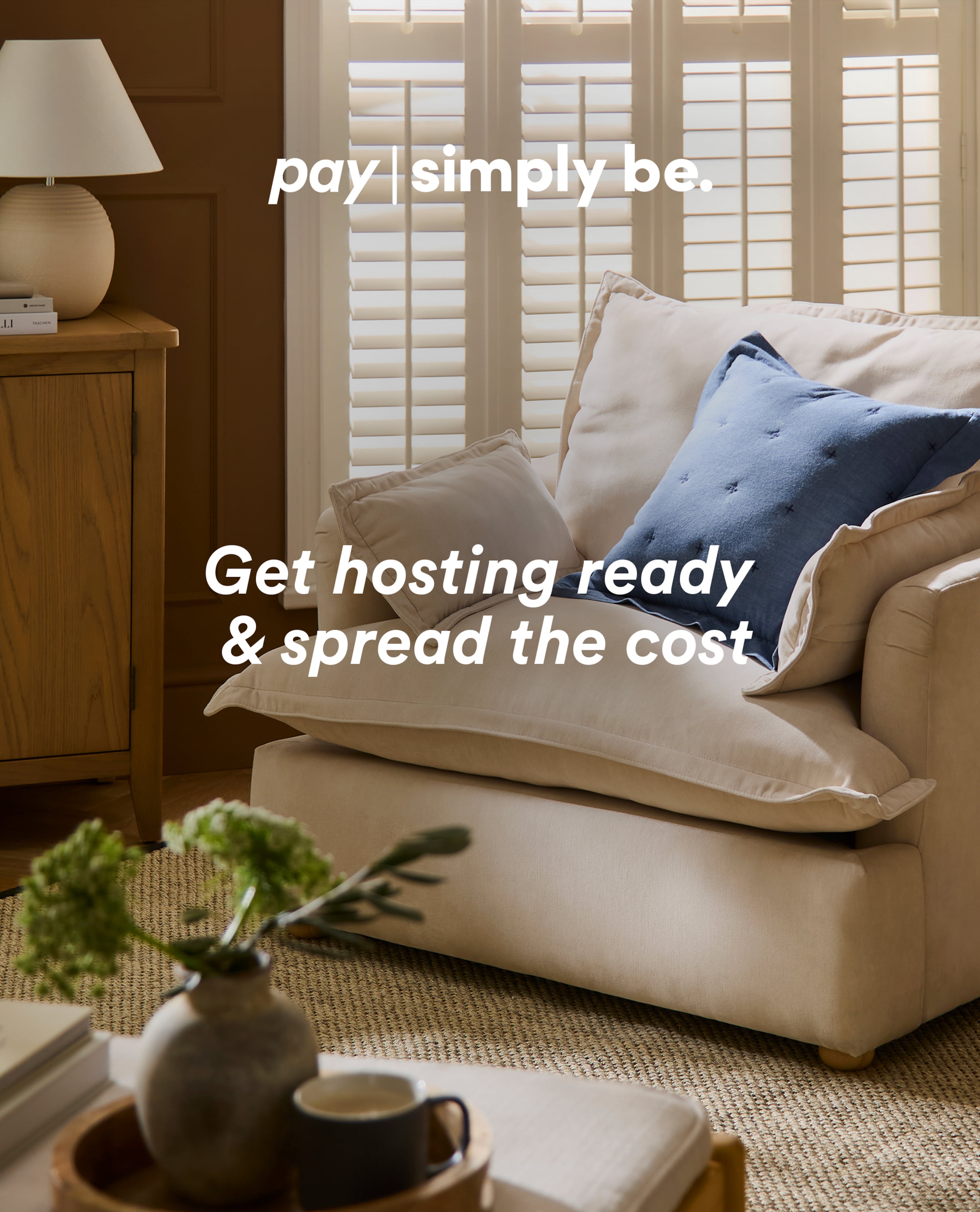 Cosy living room scene with armchair and cushions, text reads ‘Pay Simply Be – Get hosting ready & spread the cost