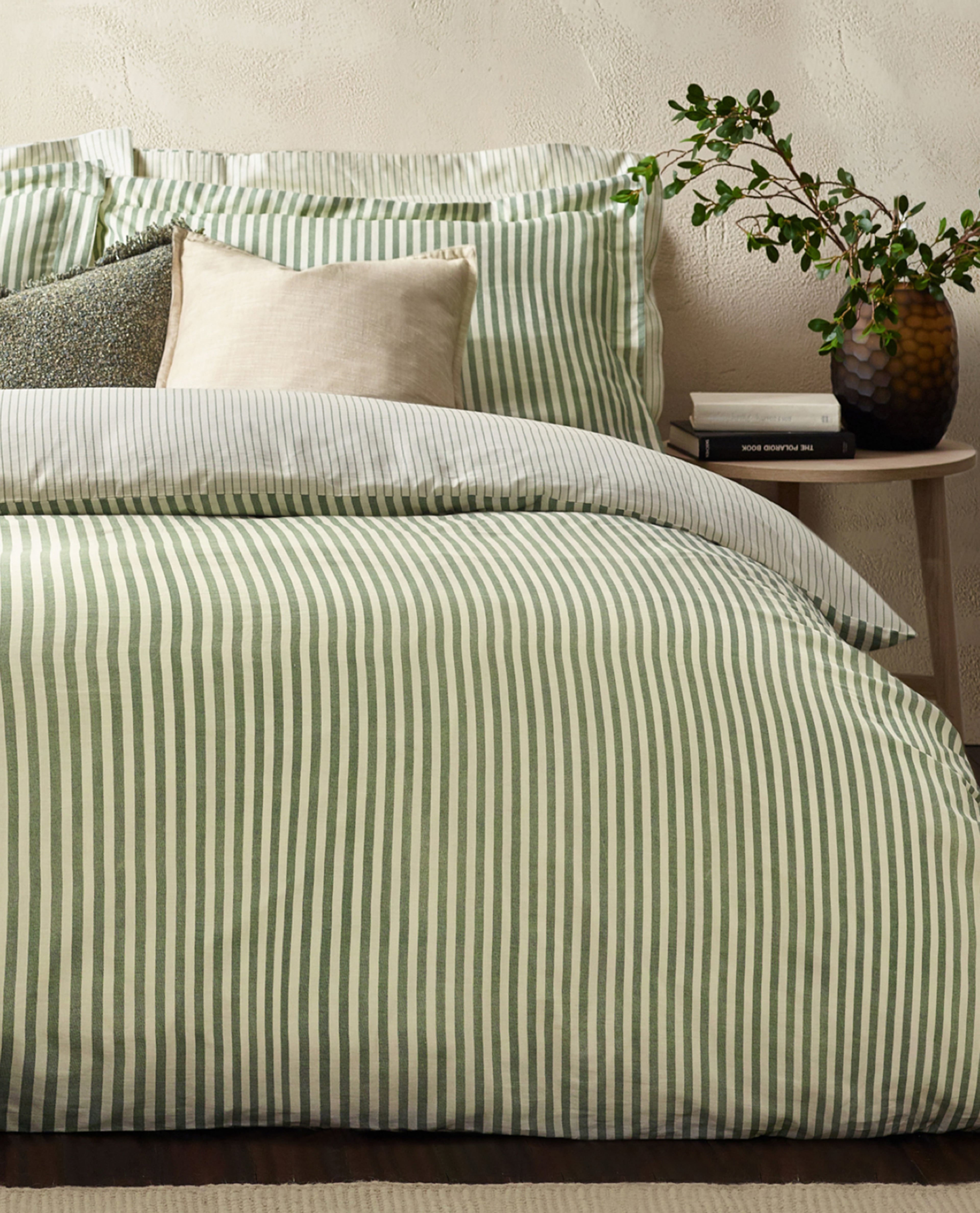 green bedding with cream pillows 