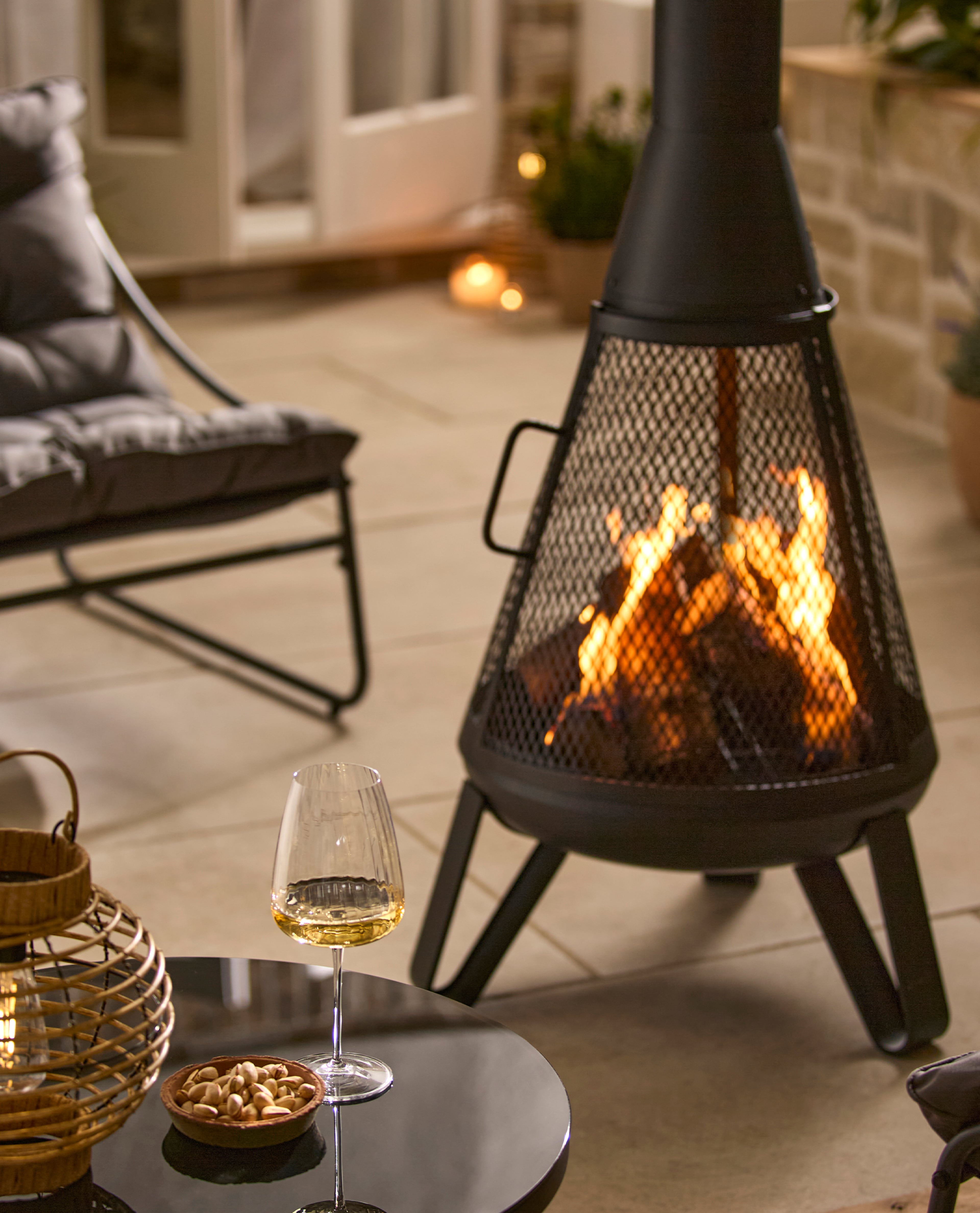 garden setting with fire pit with a small table showing a glass of wine 