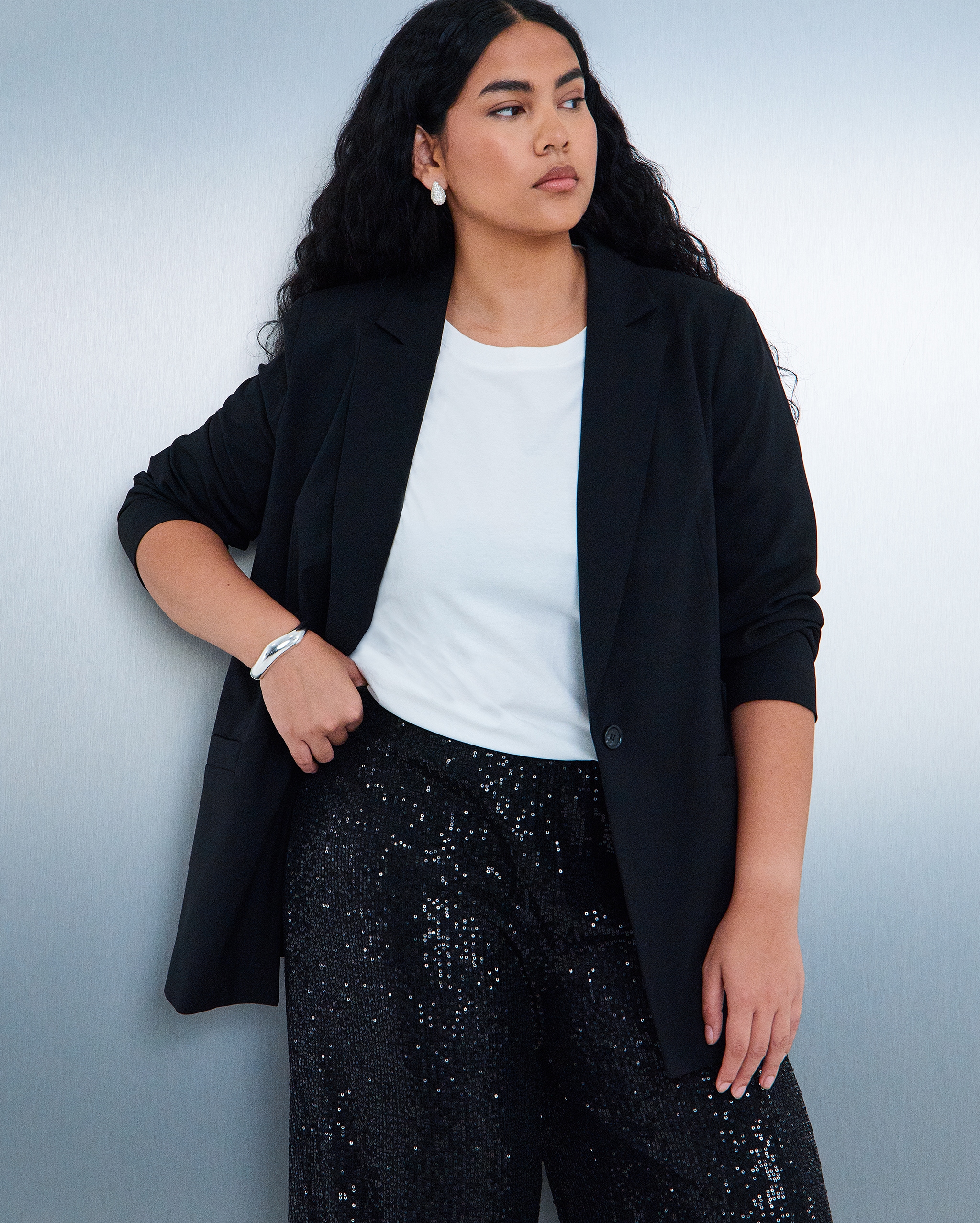 Model wears sequin trousers and smart top in black