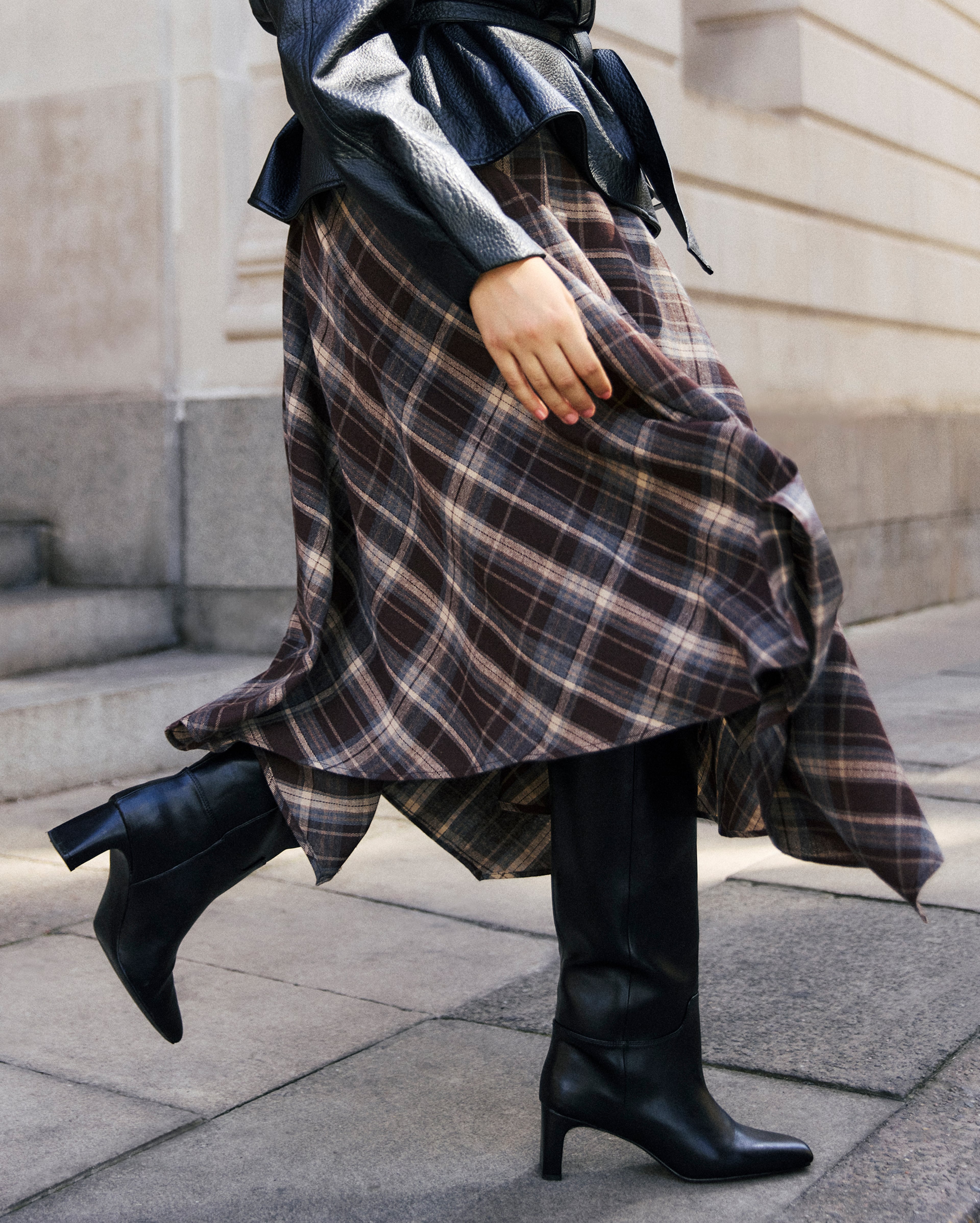 Model wears new season high boots and check skirt
