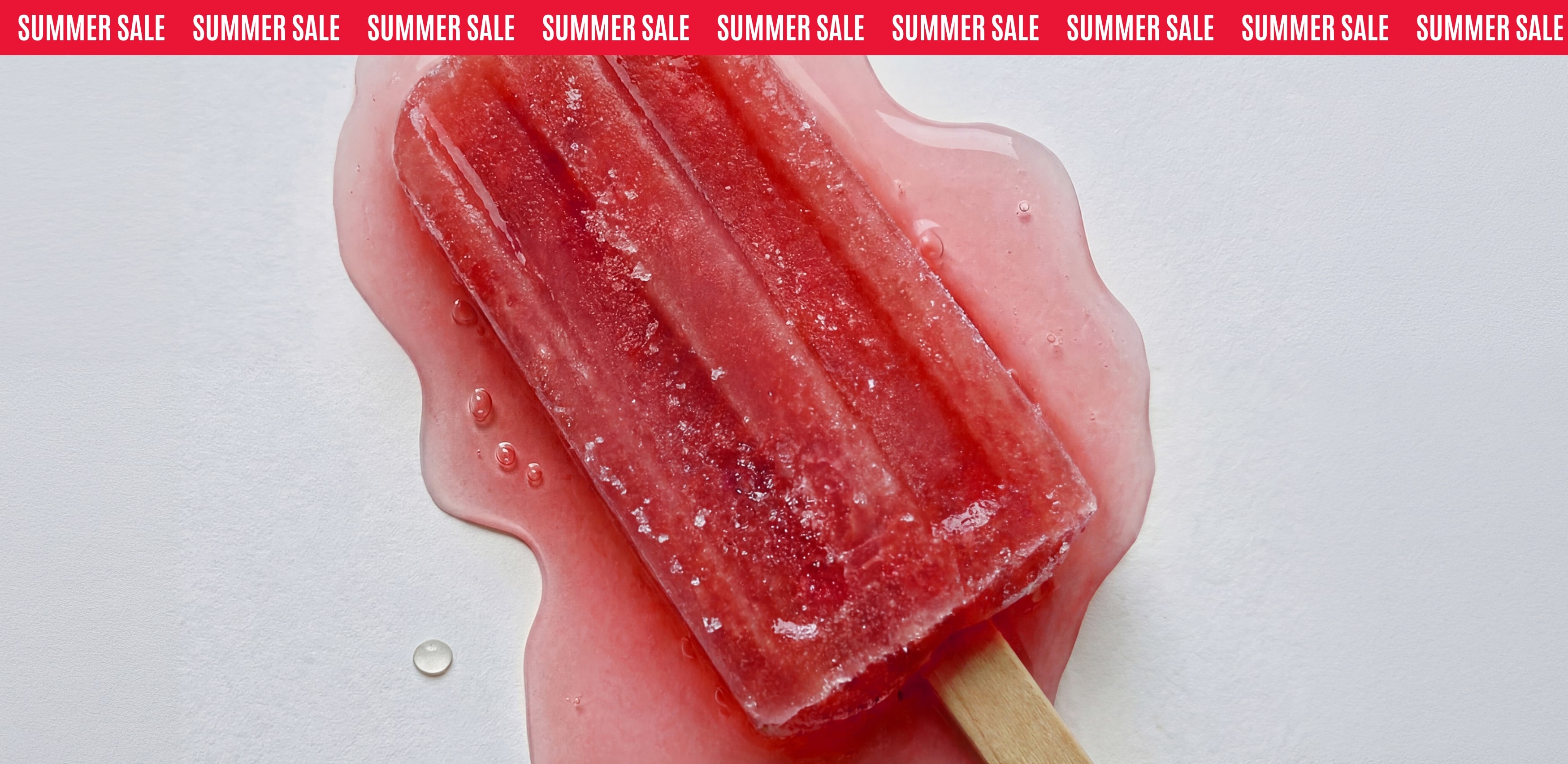 Melting red ice lolly on a white surface, beneath a Summer Sale banner.