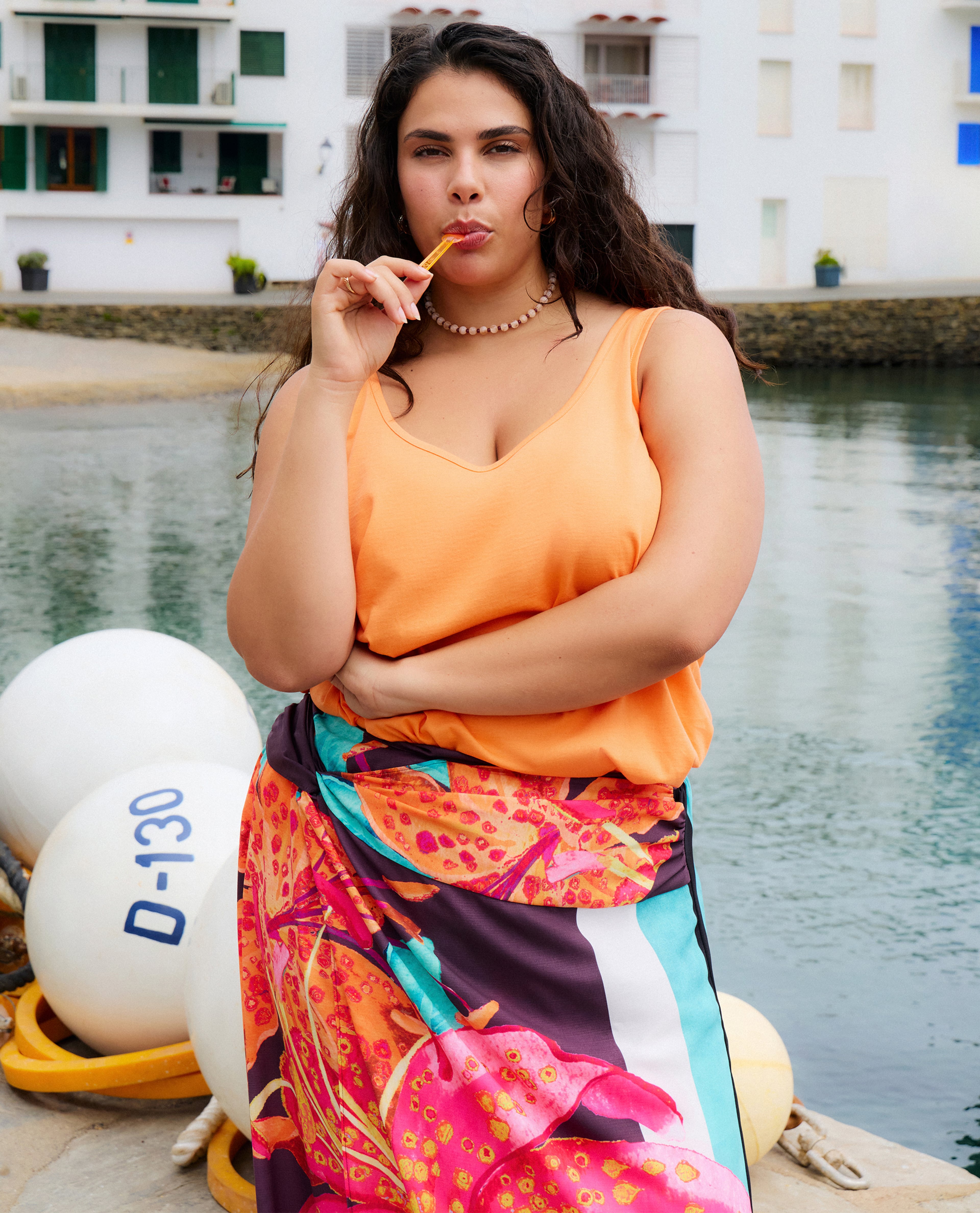 Model wears orange top and sarong