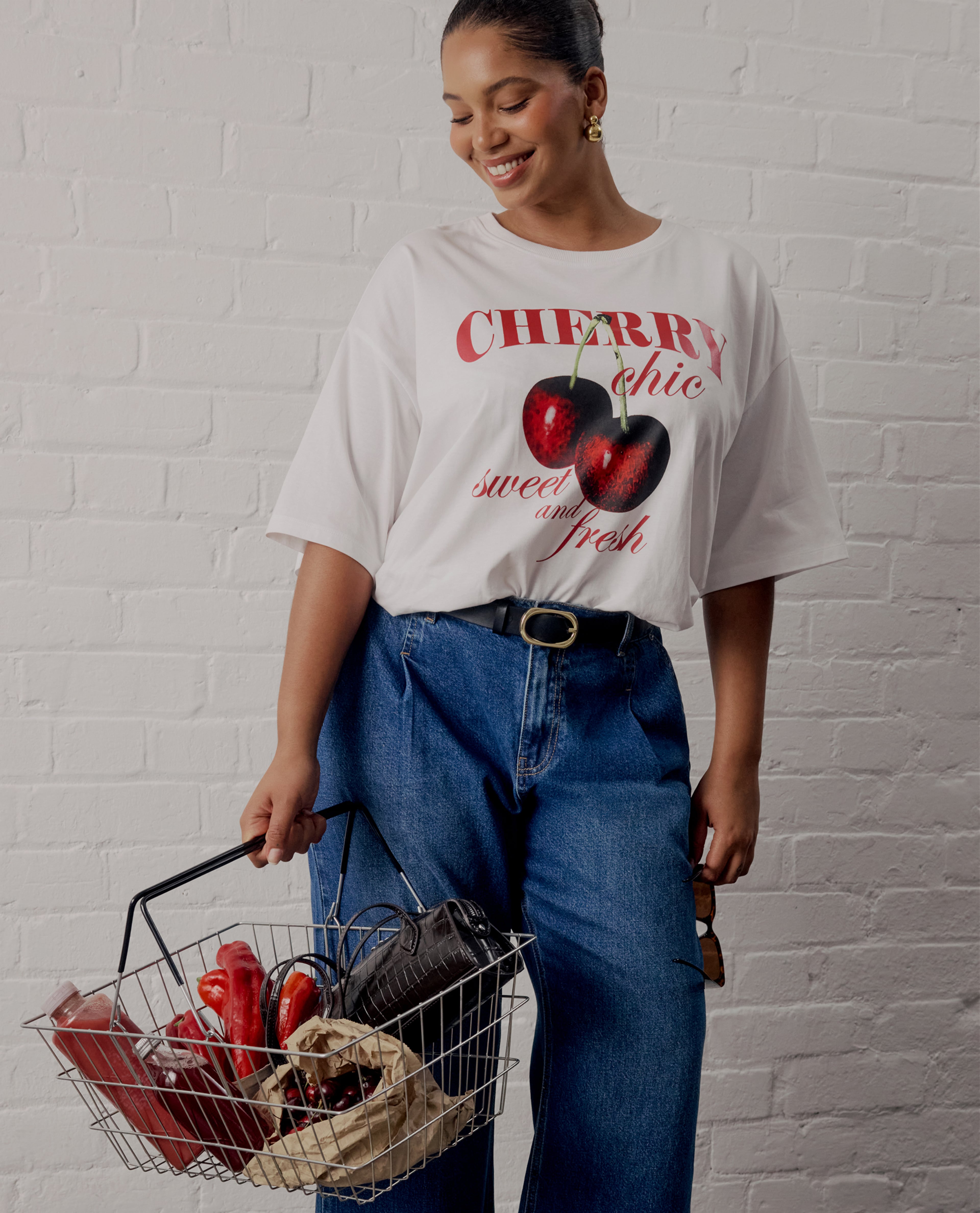 Model wears cherry graphic tee and jeans