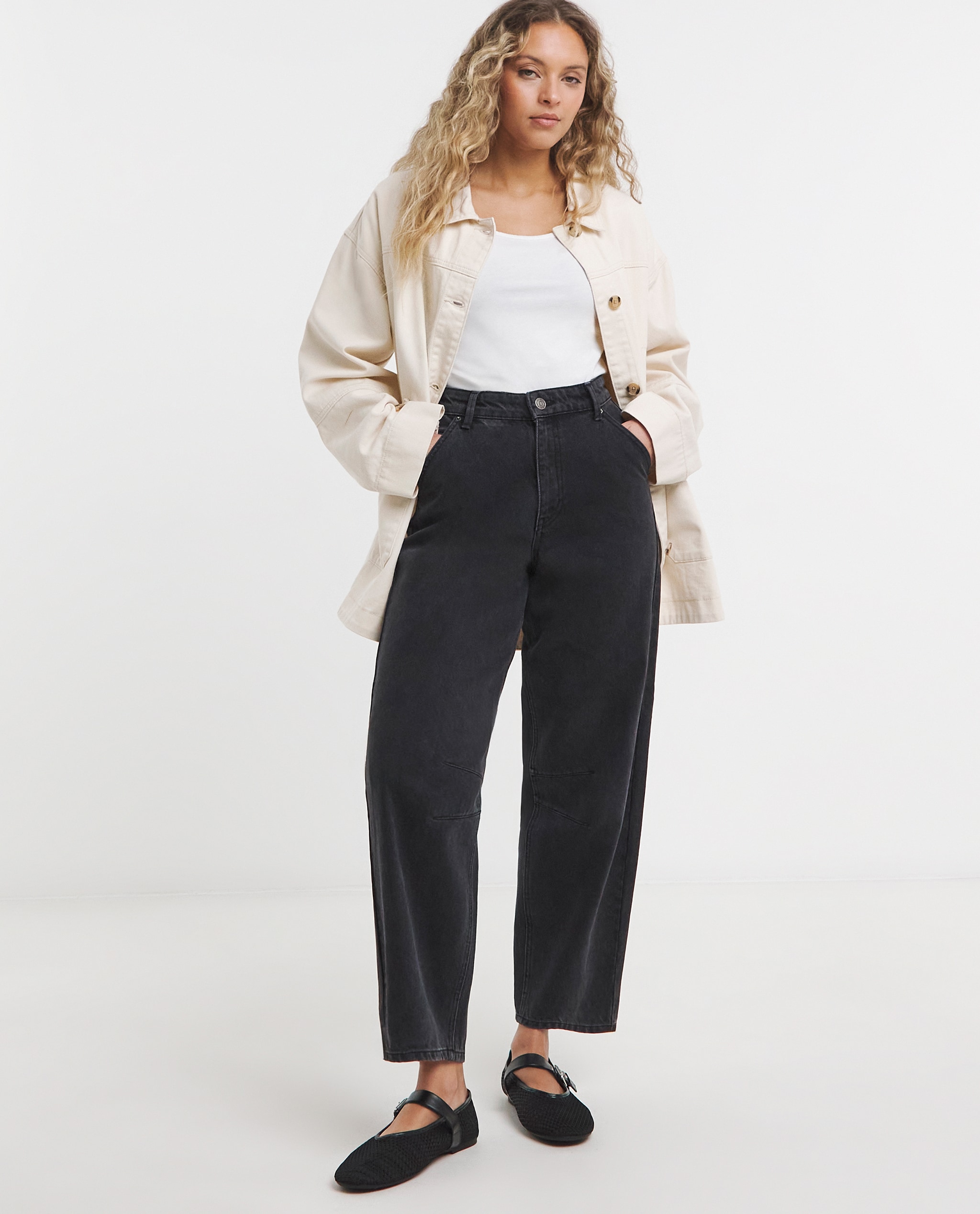 Model wearing dark wash jeans with stone button through utility jacket and white vest top