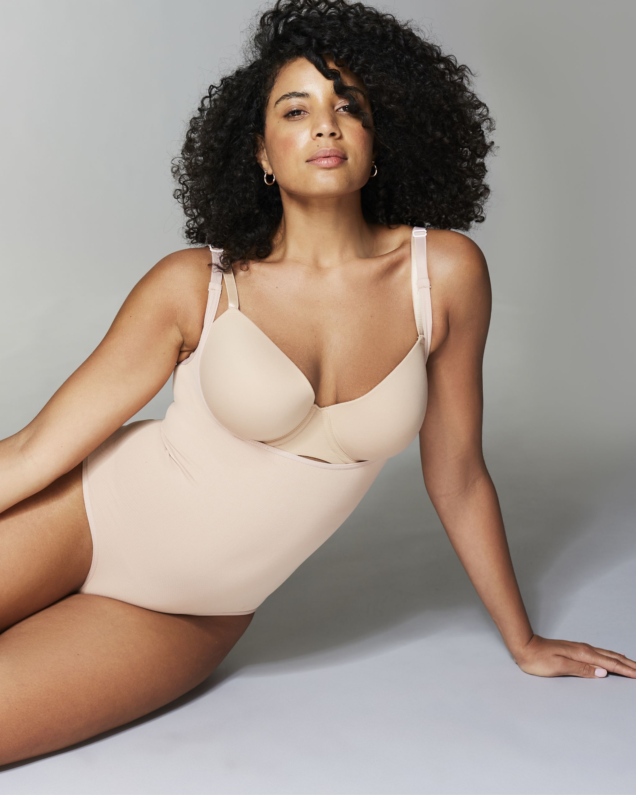 A model sat wearing a nude coloured all in one underwear set