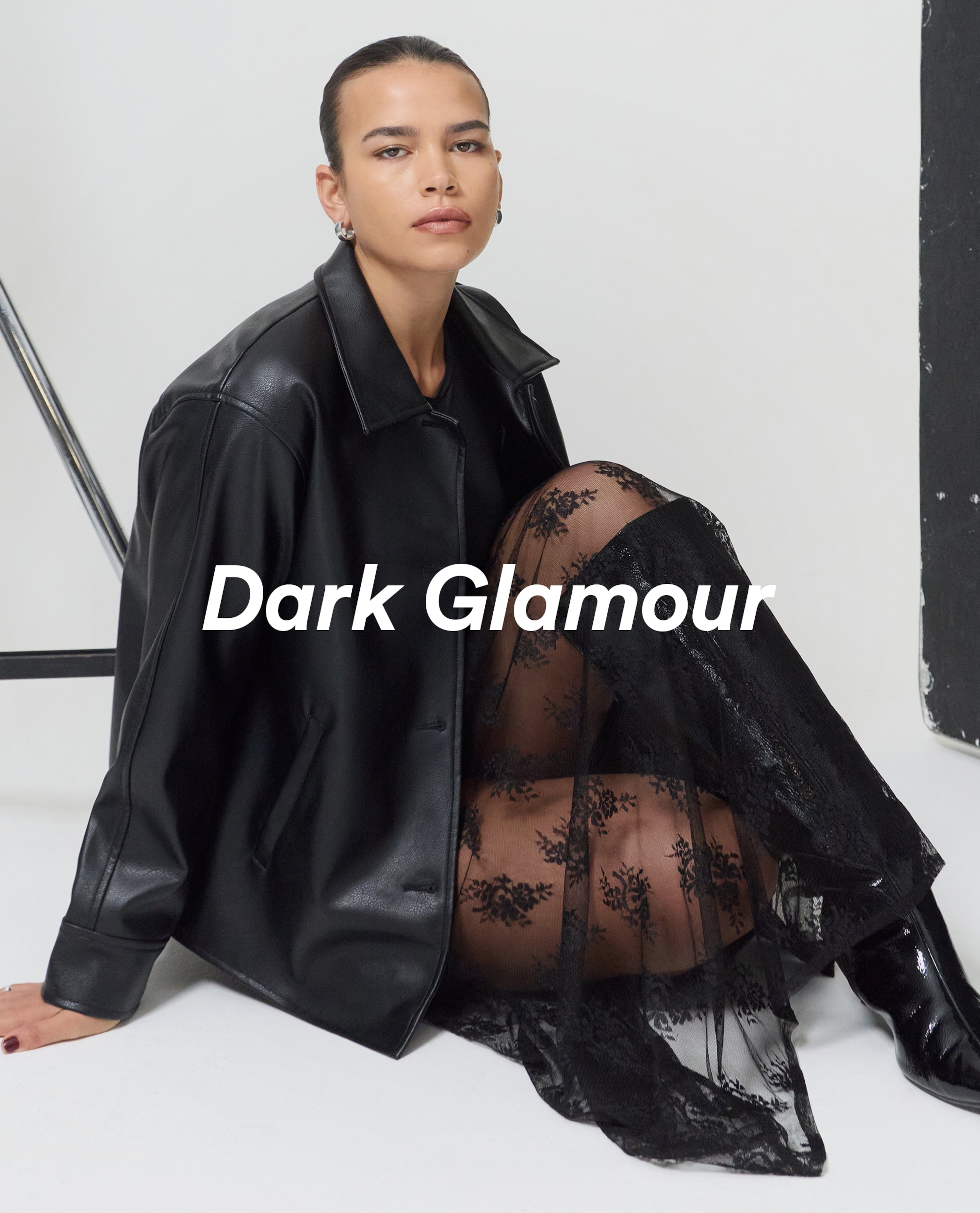Model wears black leather jacket and lace skirt in black