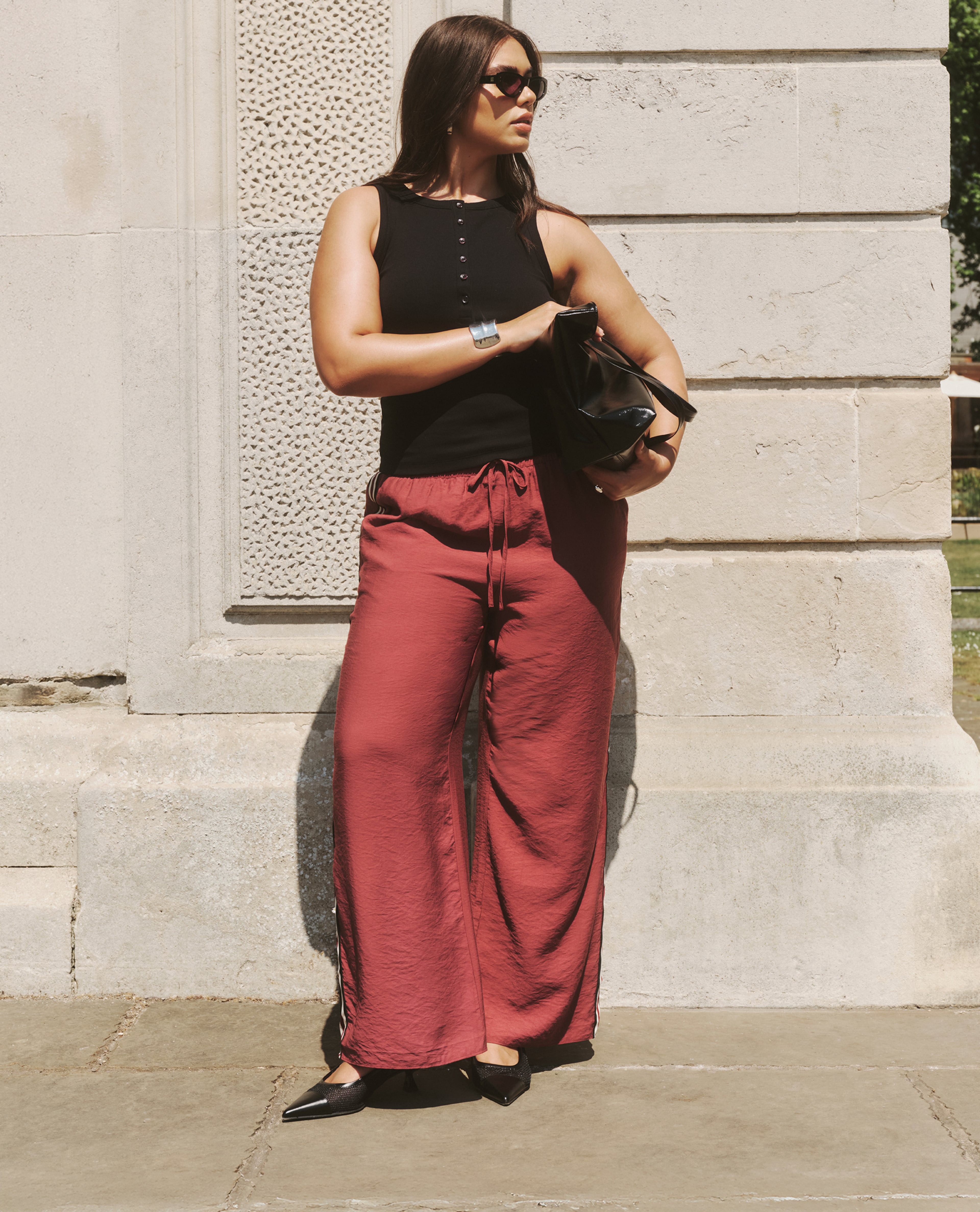 model wearing glasses black top brown trousers