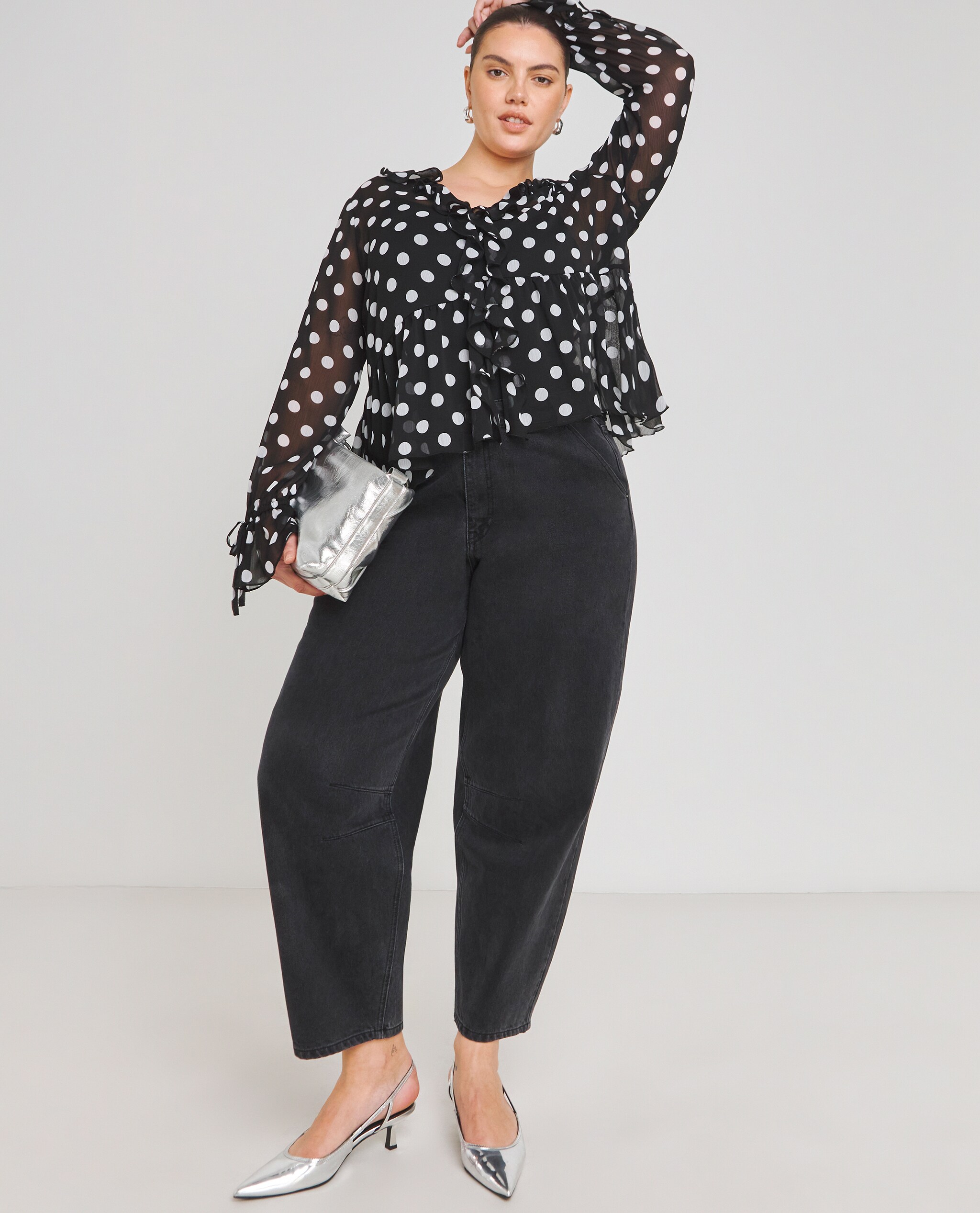 Model wearing wide leg jeans with spot print ruffle front blouse
