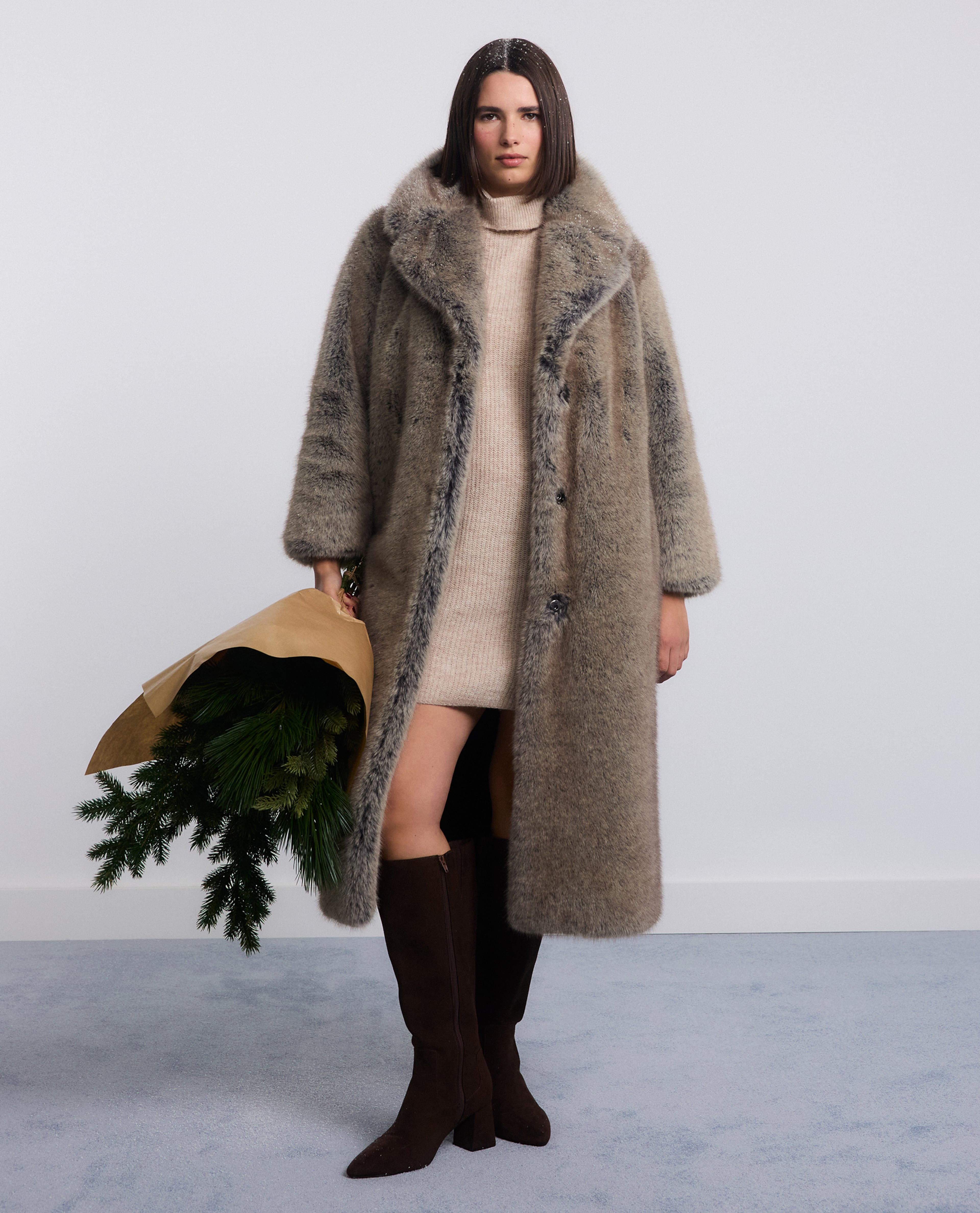 Model wears long faux-fur coat with knitted dress and boots