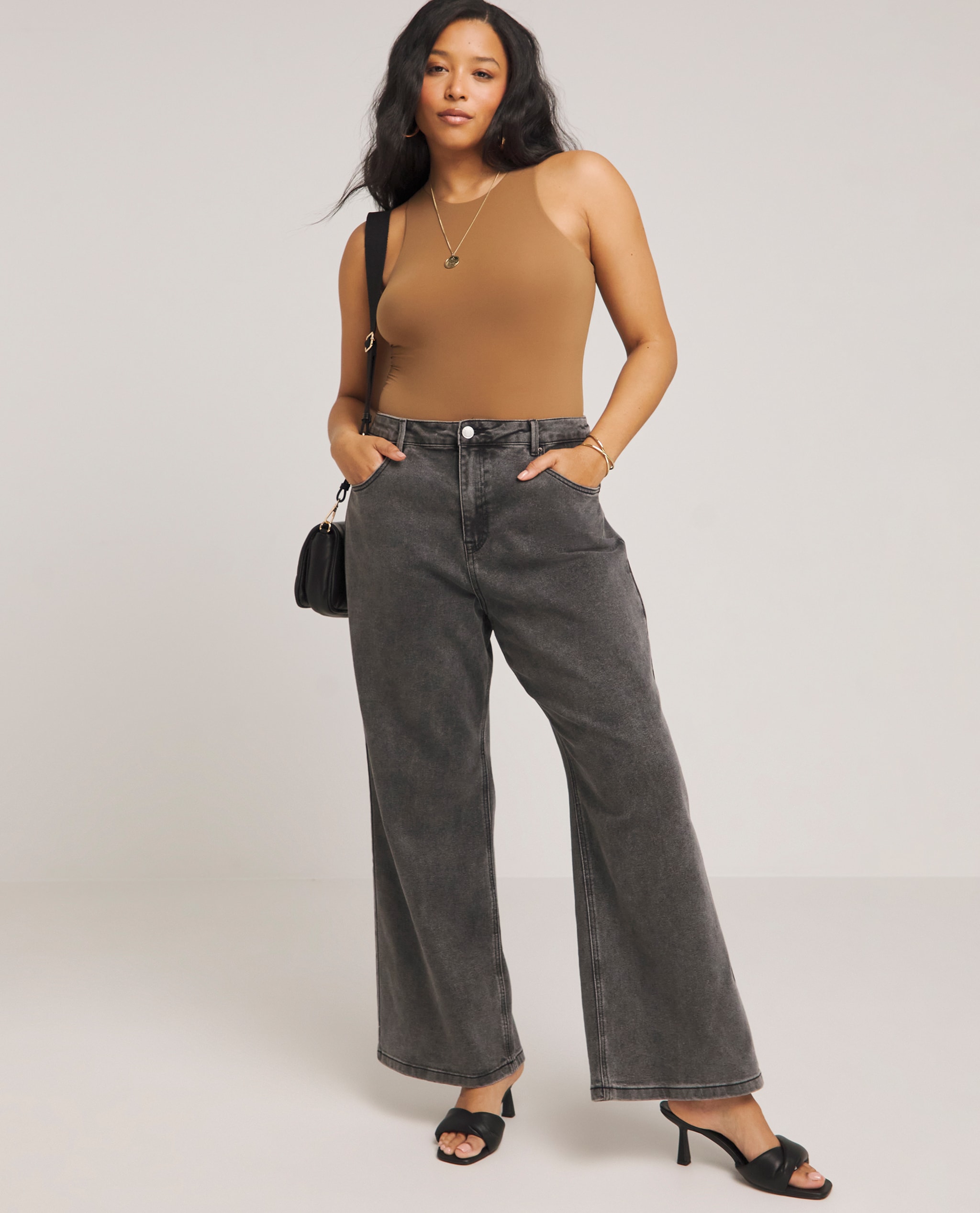 Model wearing dark grey wide leg jeans with smoothing racer vest bodysuit