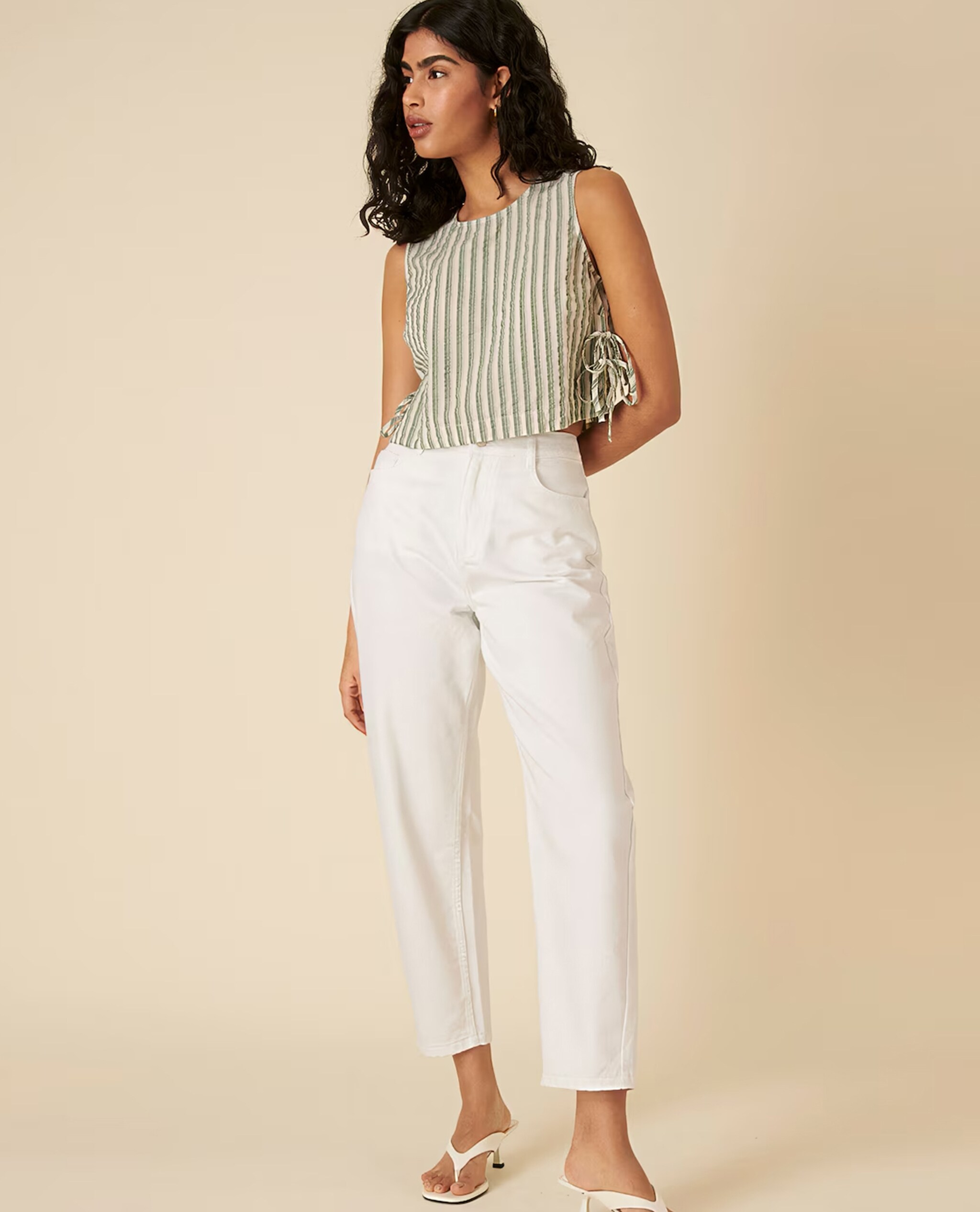 Model wearing white jeans with green stripe swing top