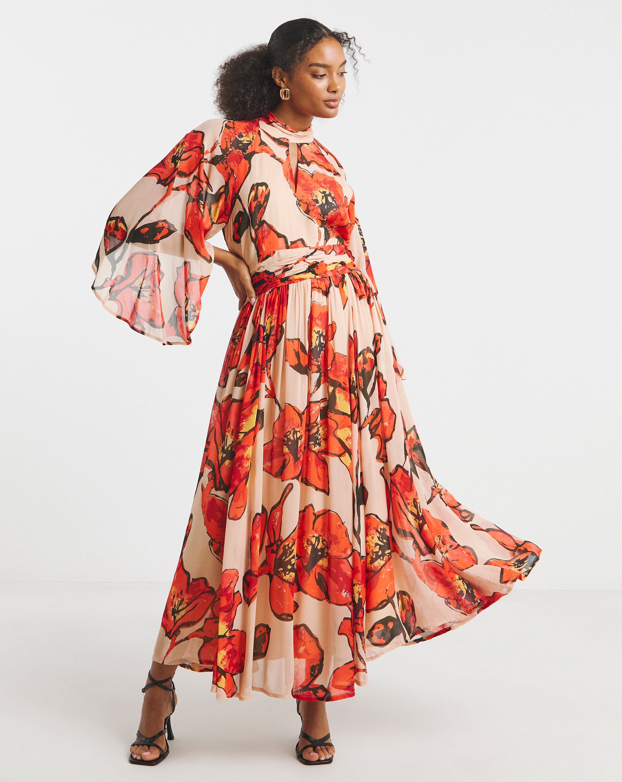 Model is wearing a Joanna Hope red floral printed maxi dress