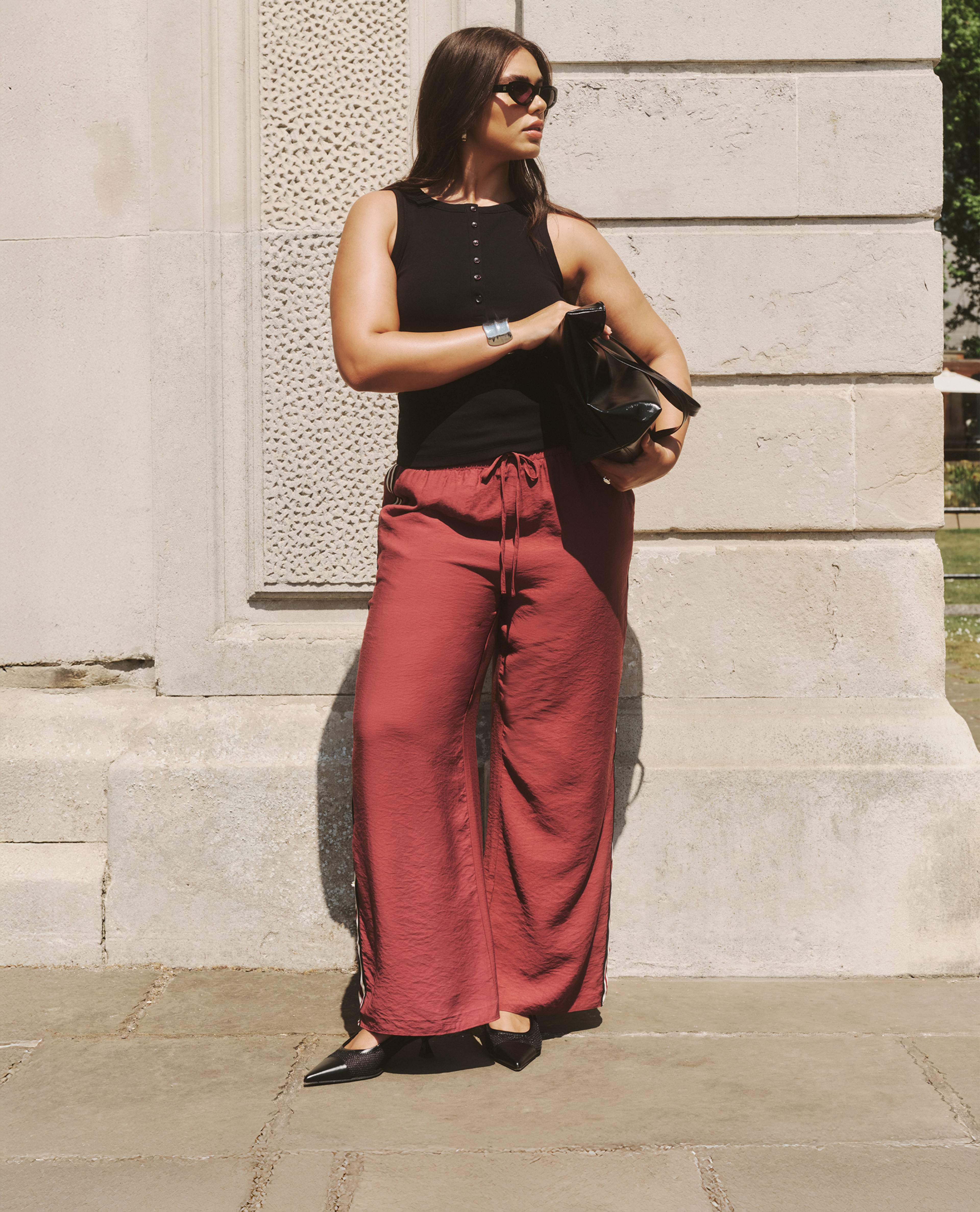 Model wears black vest and red side-stripe trousers