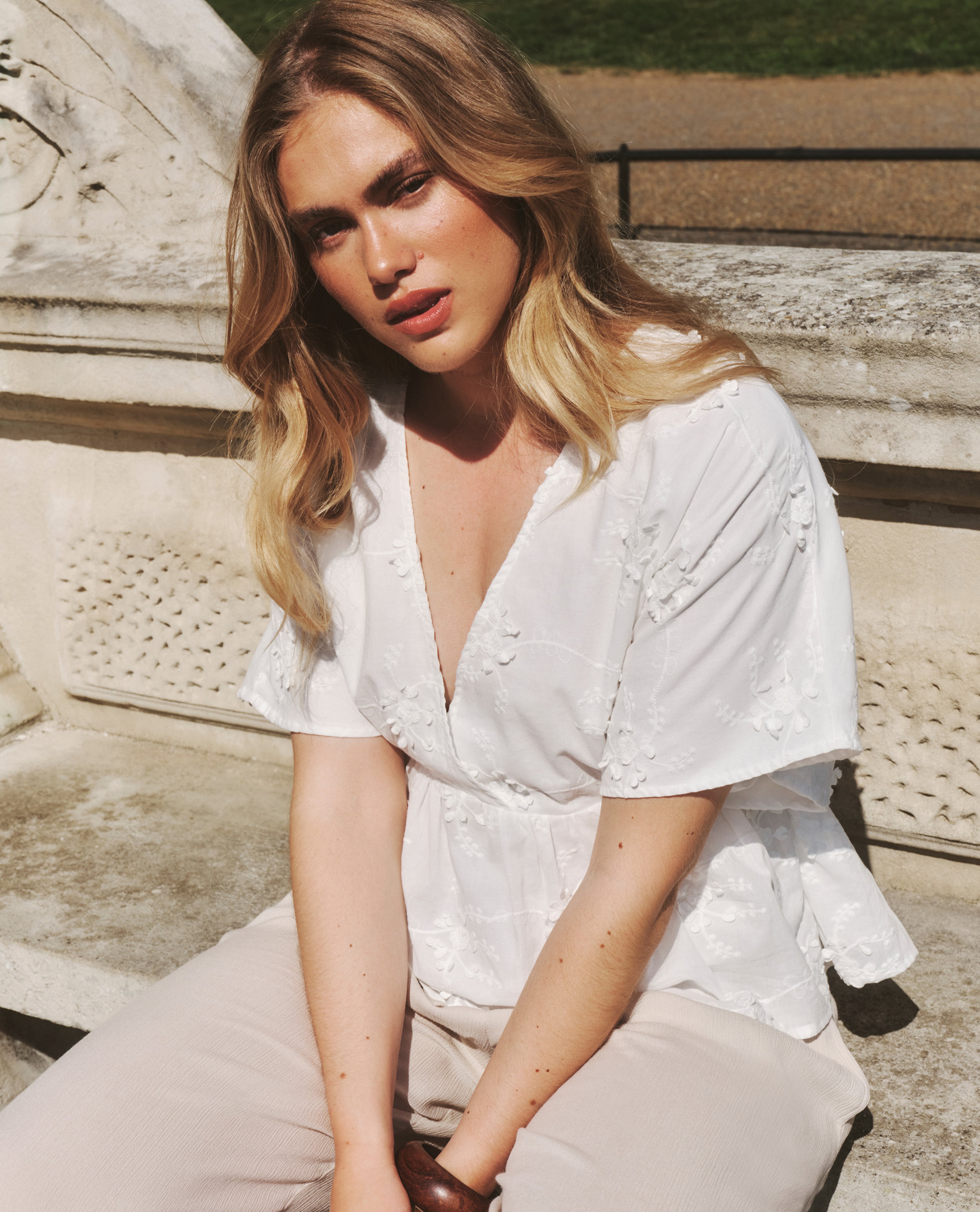 model wearing white shirt sat on bench