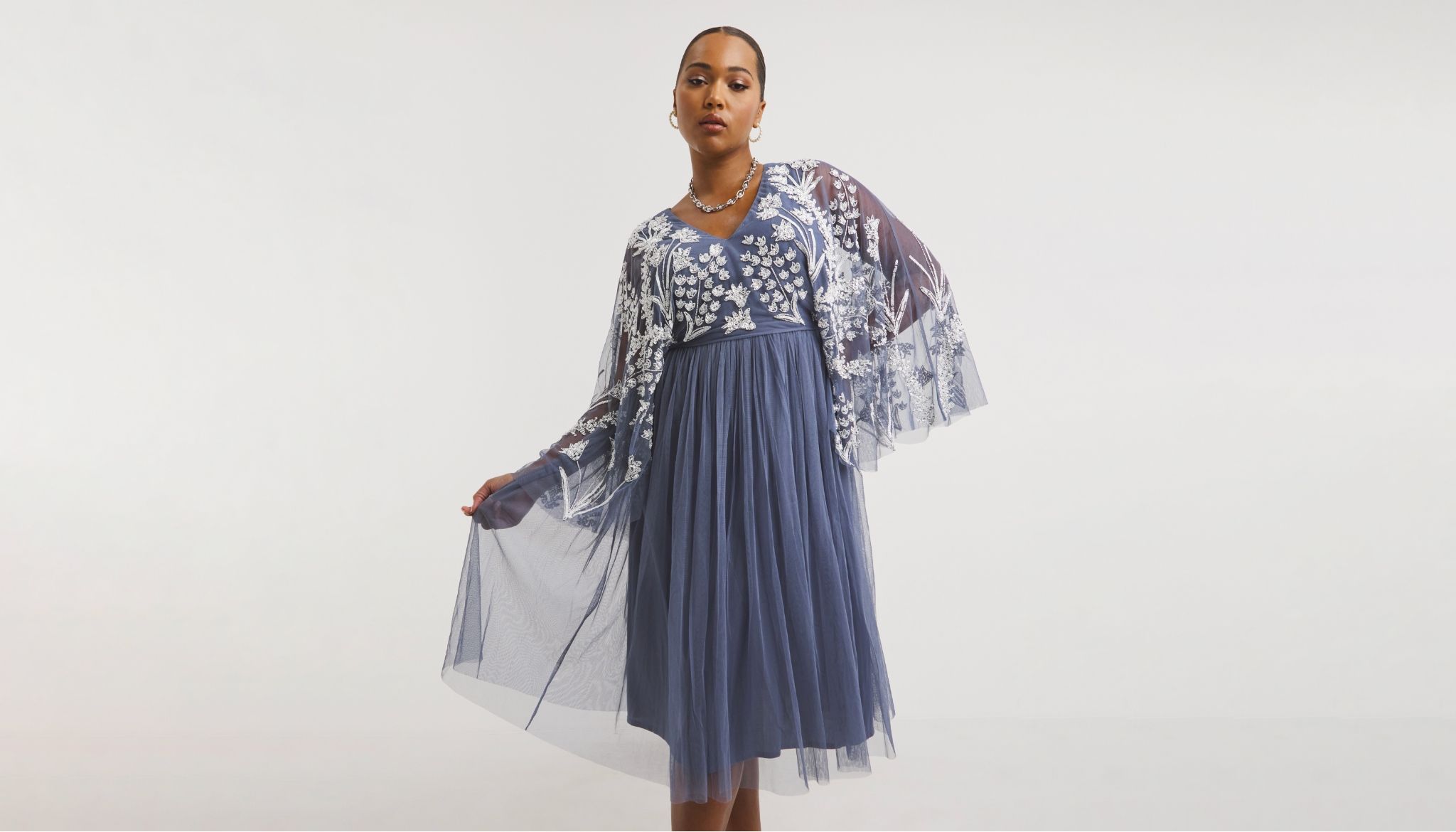 A model stood wearing a white lace and air force blue chiffon dress
