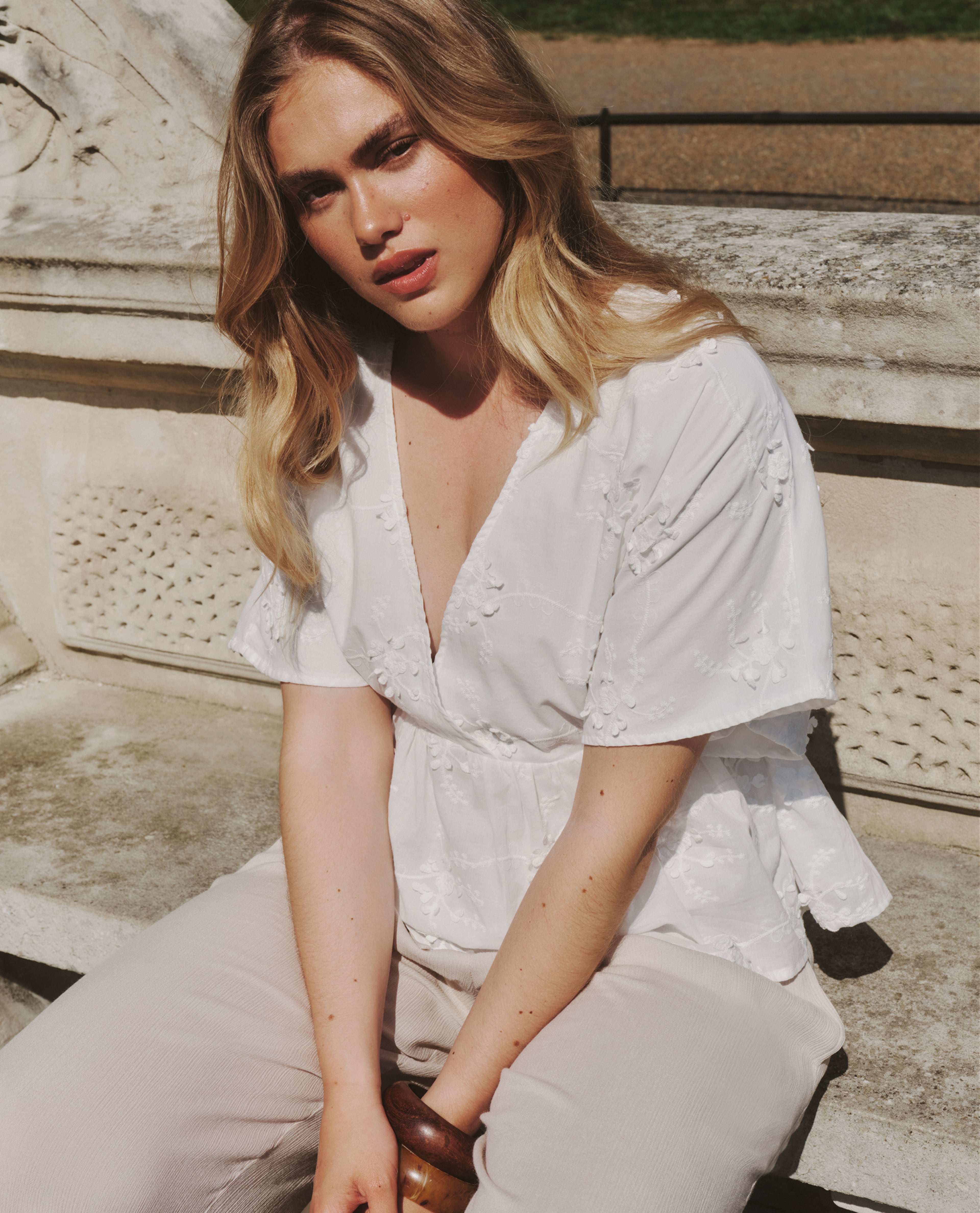 Model wears white top with embroidery detail