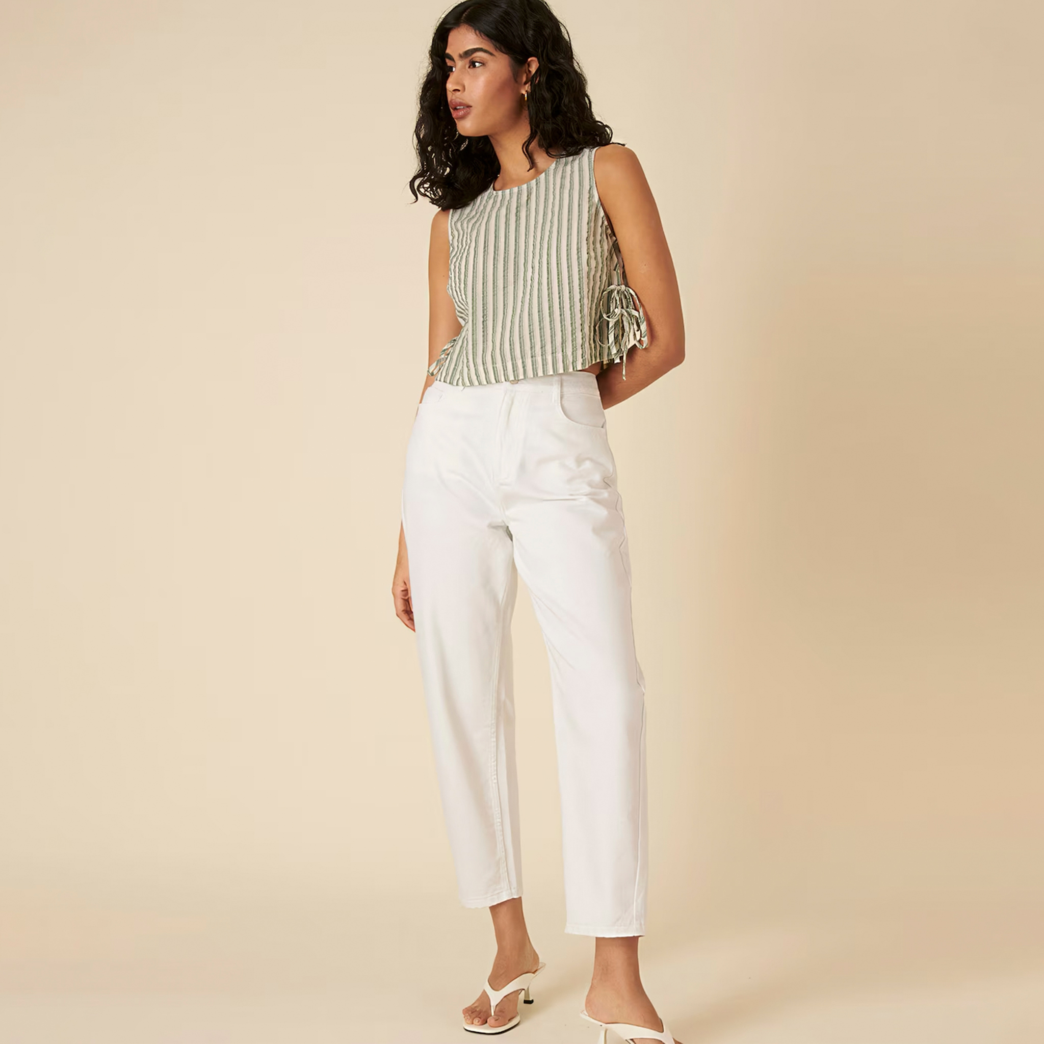 Model wearing white jeans with a green stripe swing top