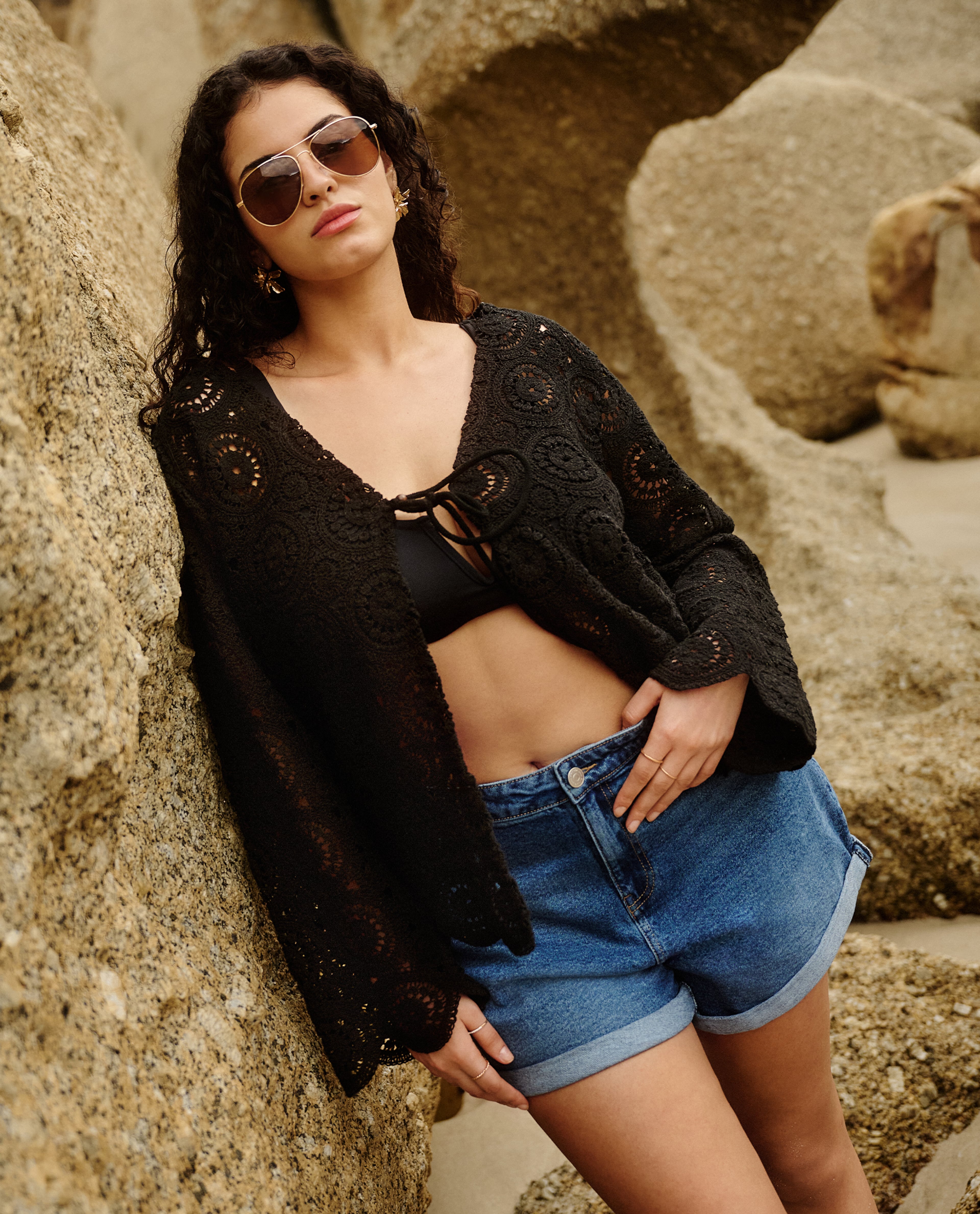 Model wears black crochet top and denim shorts