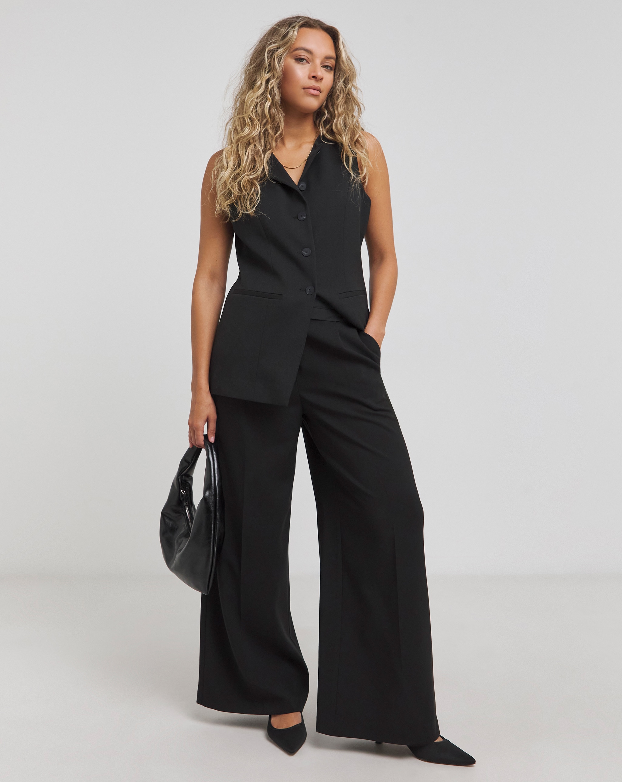 Model wears black waistcoat and matching tailored traousers