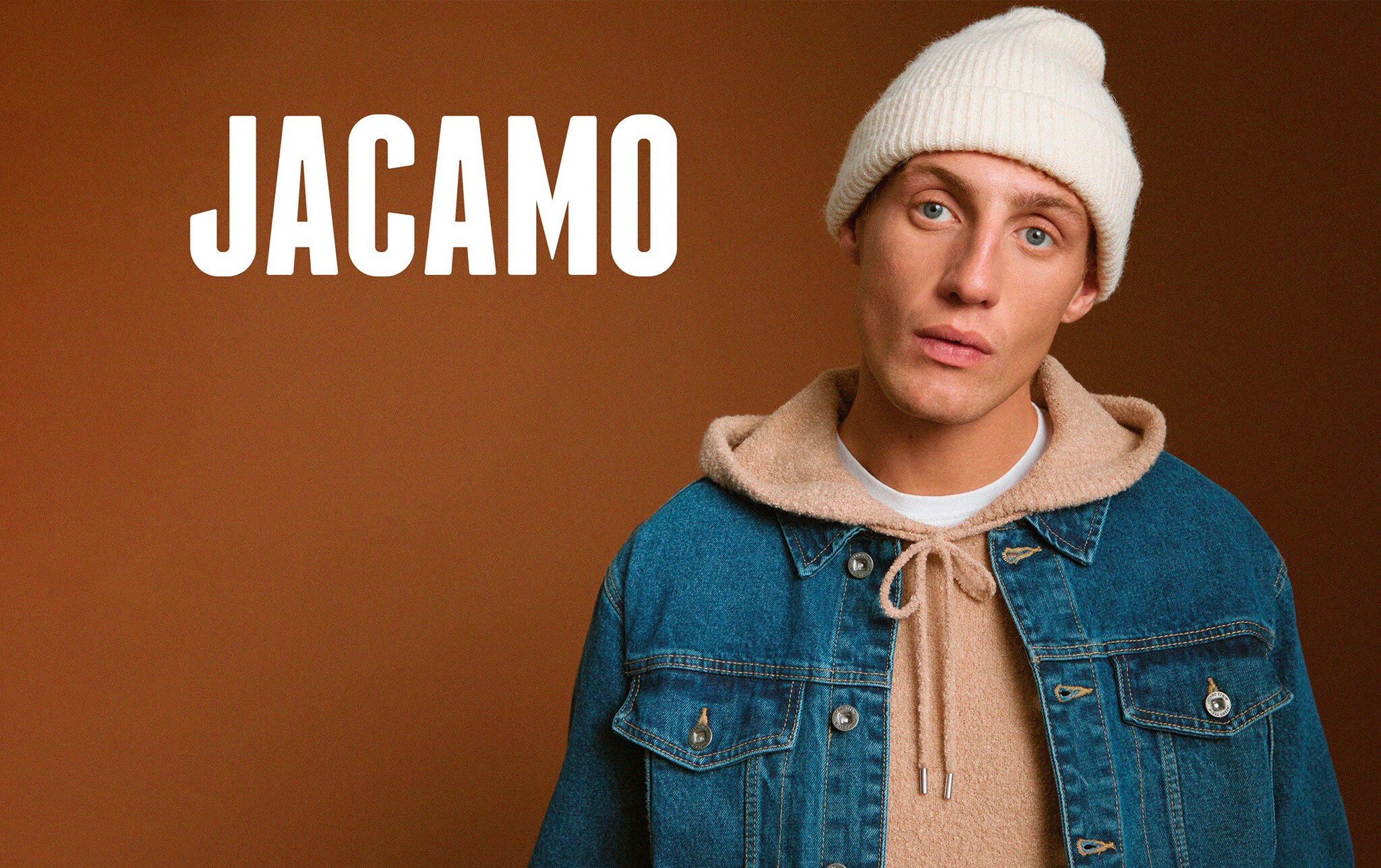 A man wearing a bobble hat and a denim jacket
