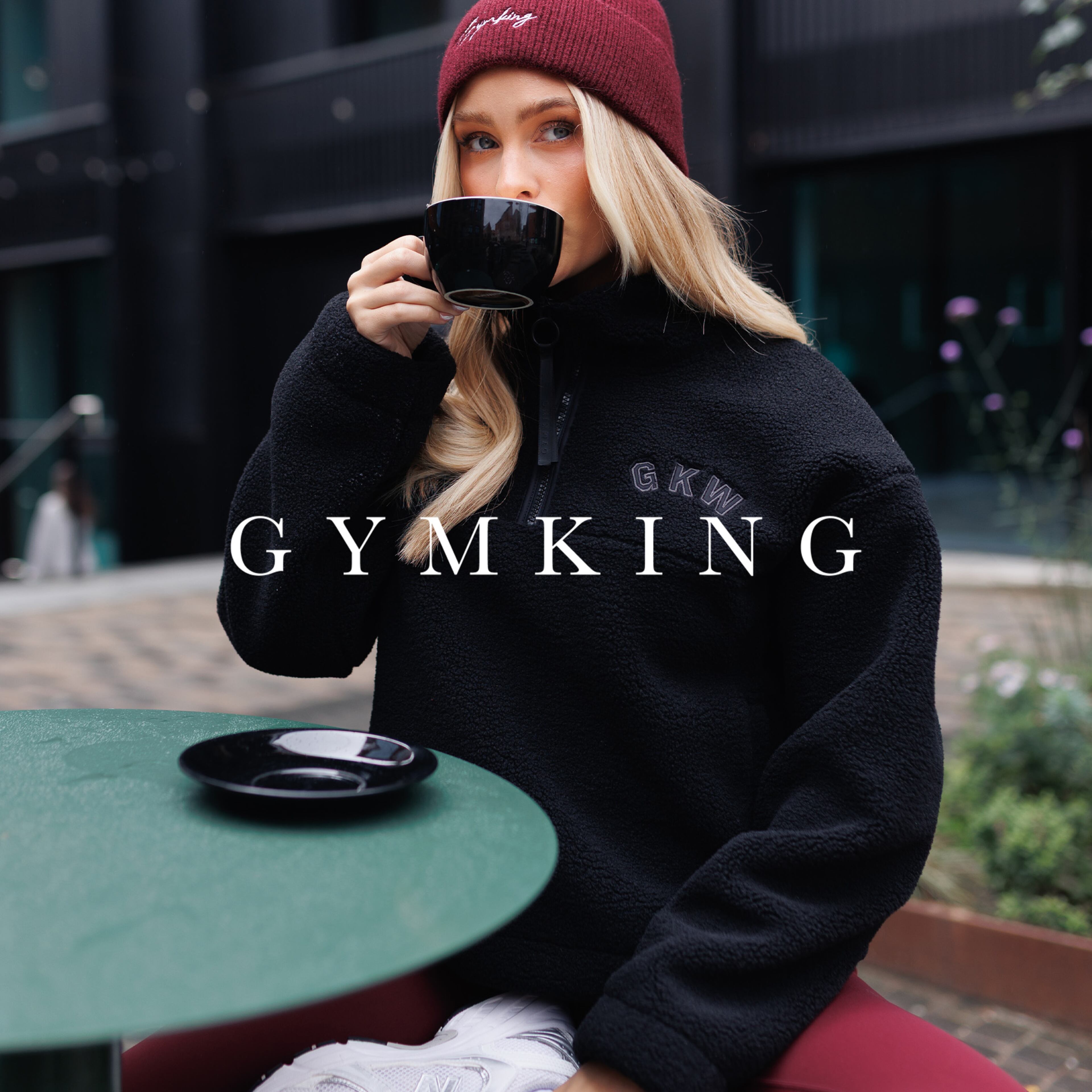 Model wears black zip top and beanie hat from Gym King