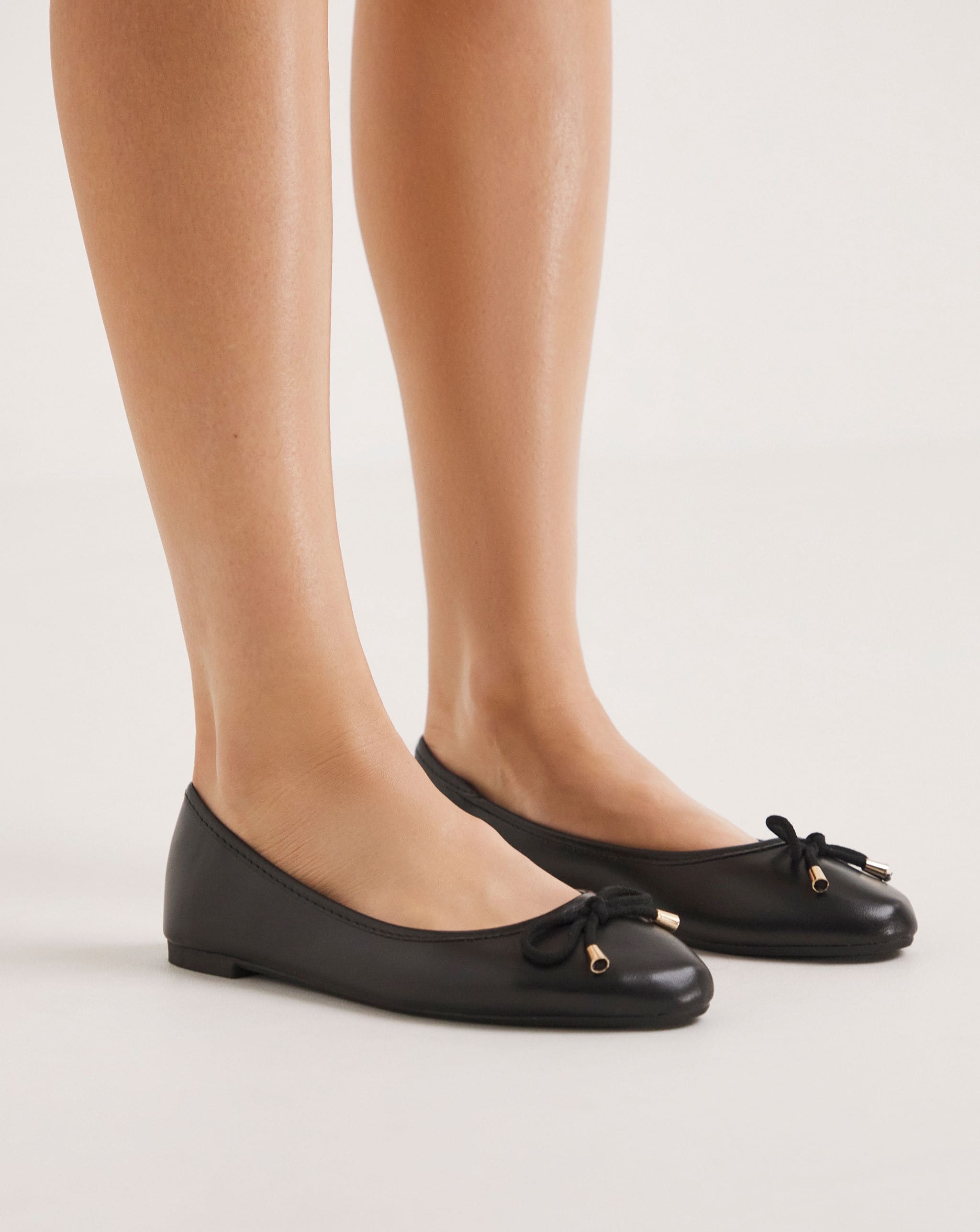 Model is wearing a pair of black Selena Classic flat ballerina shoes