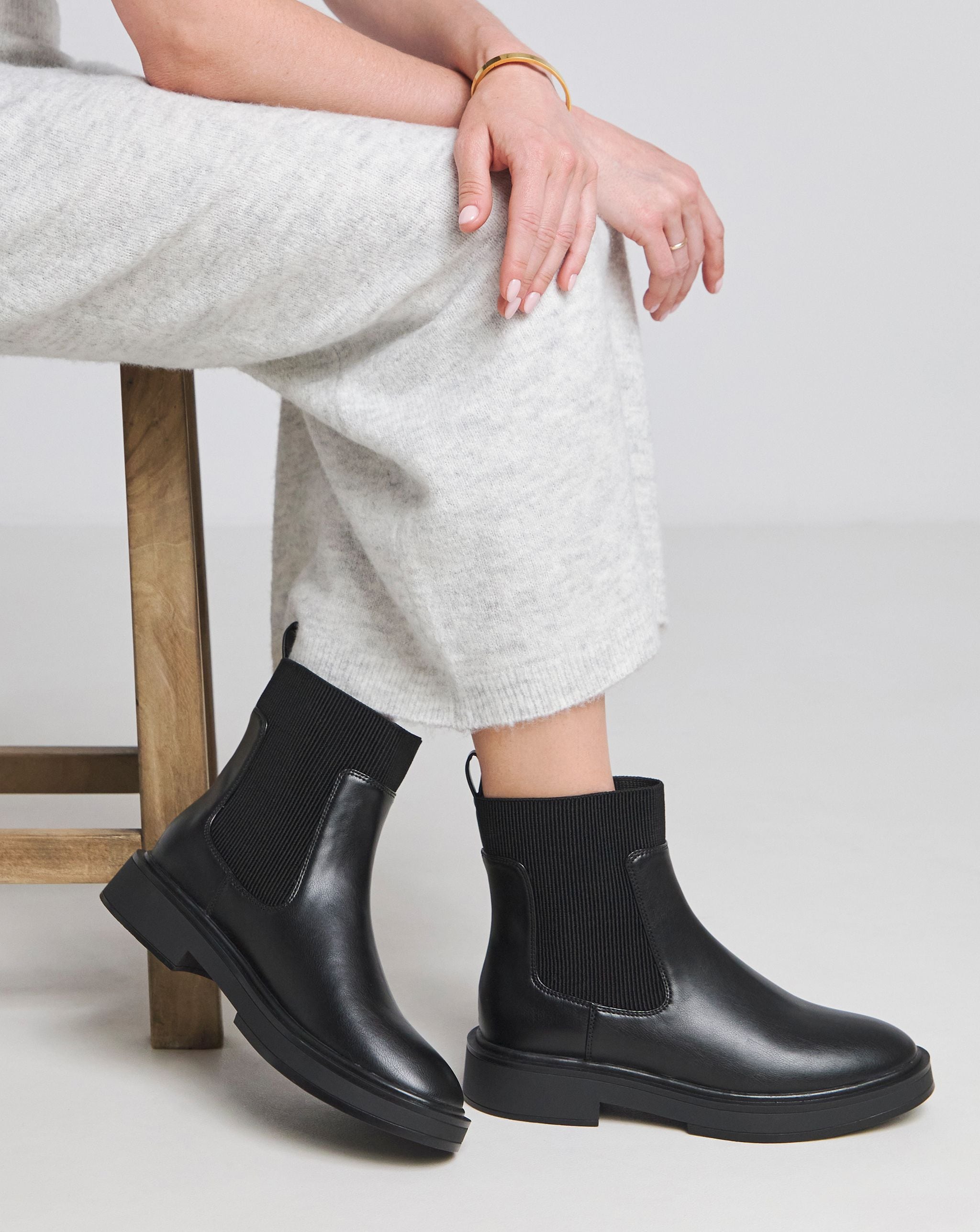 Model is wearing a pair of black Rue Classic Chelsea ankle boots