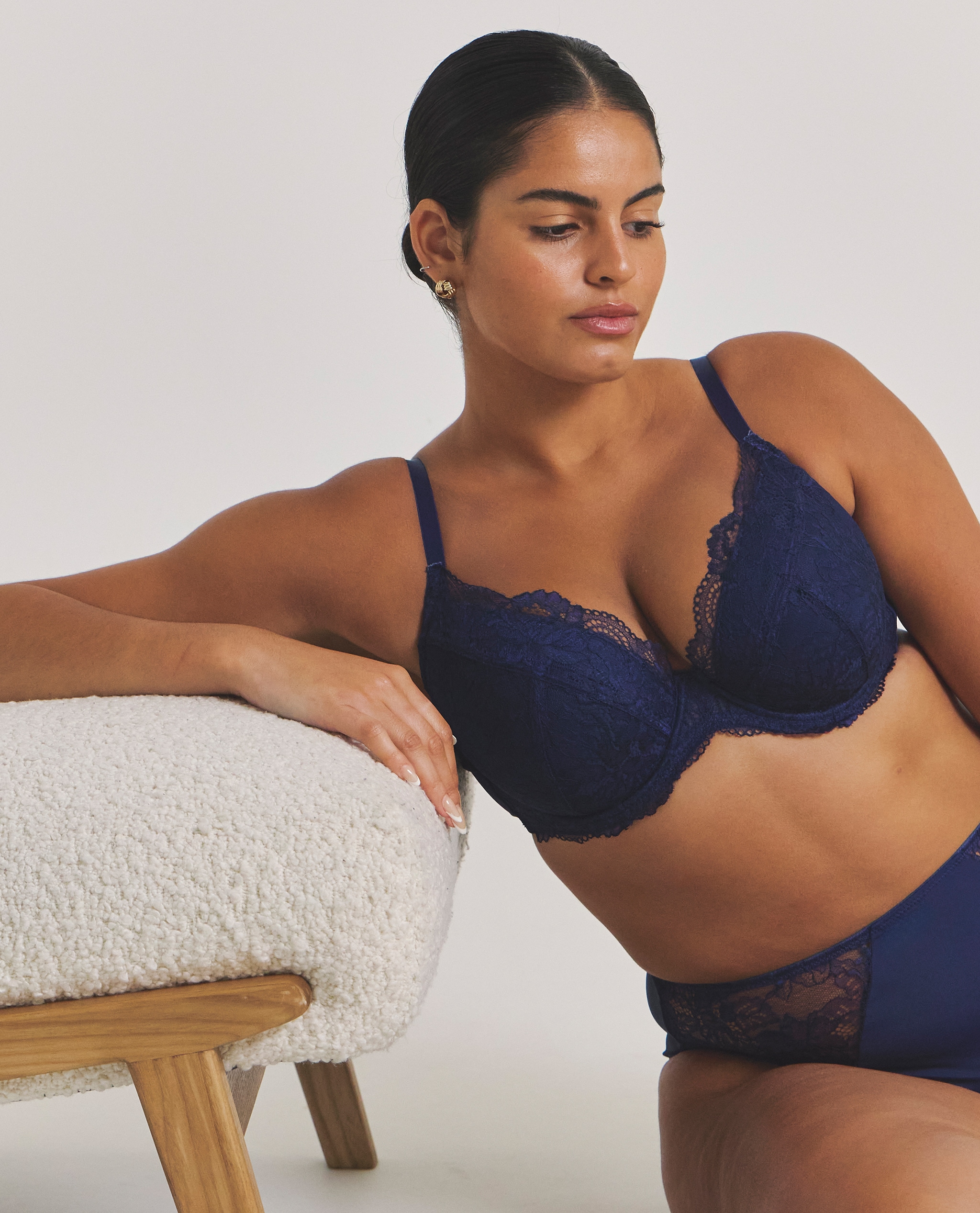 Model is wearing a navy Pretty Secrets New Ella padded plunge wired bra with matching knickers