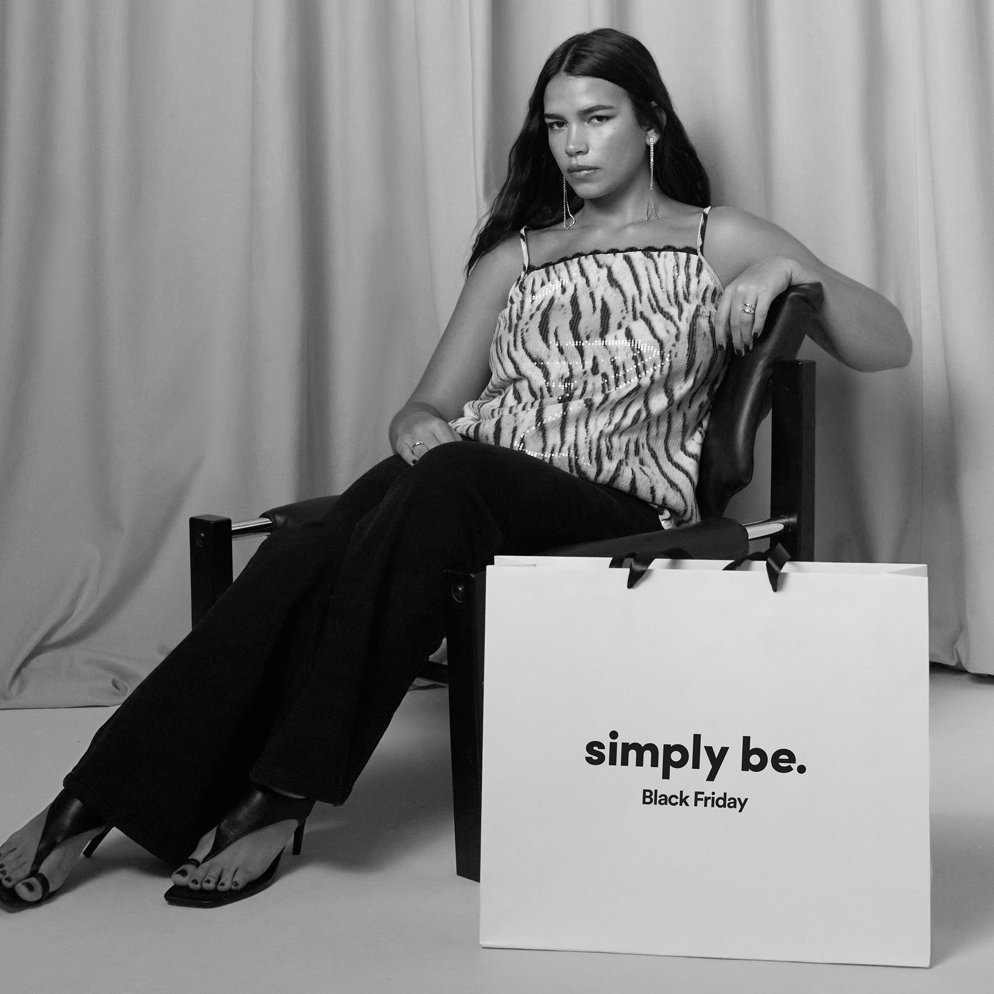 A model is wearing a black and white boob tube top with a pair of black trousers.