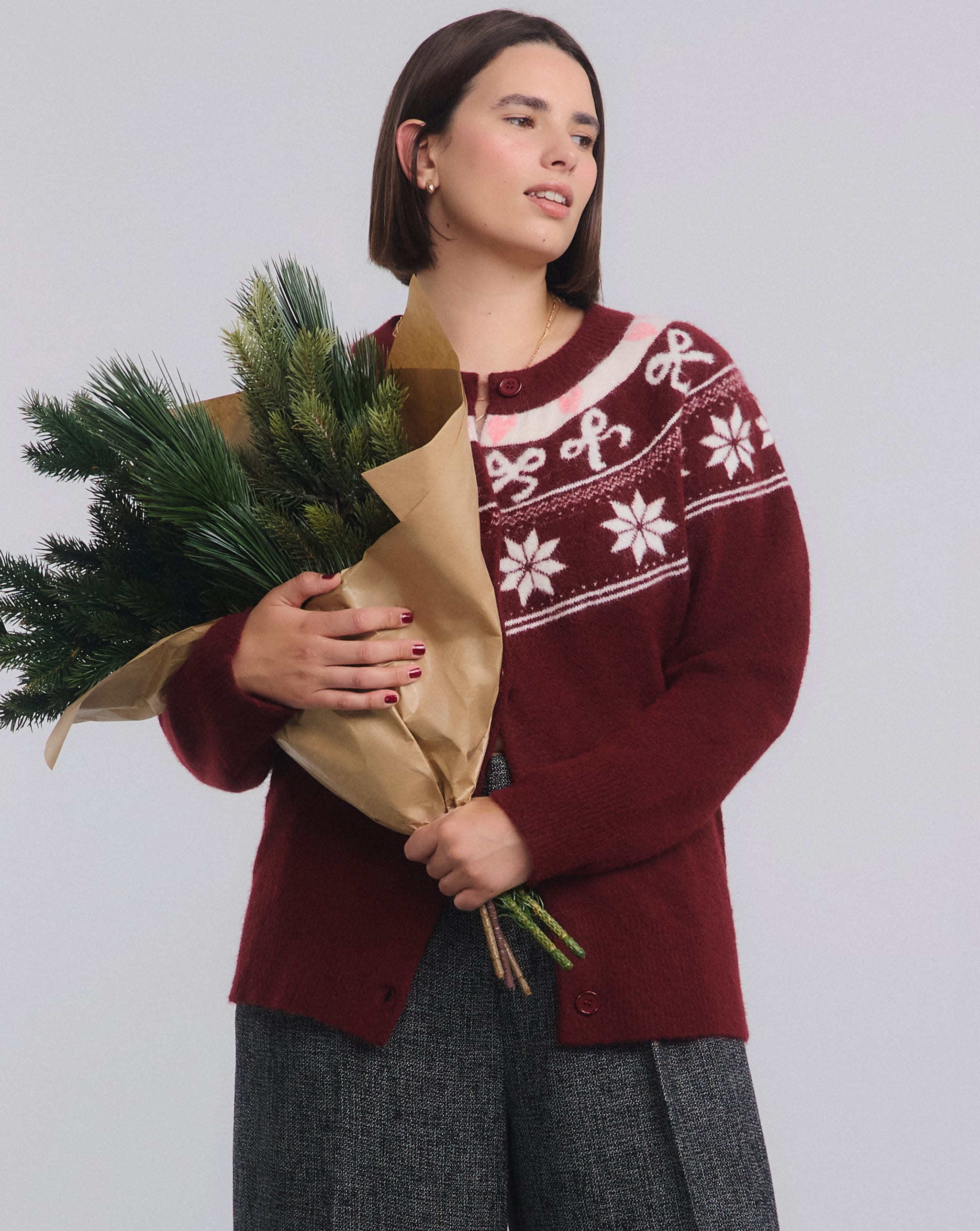 Model holds bunch of seasonal flowers and wears Christmas knitwear