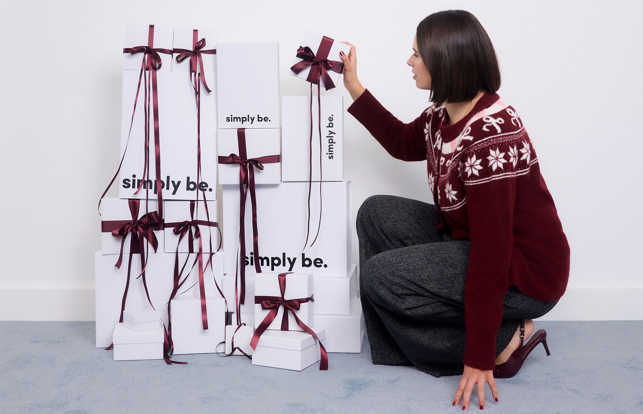 model crouched down touching white bags with bows
