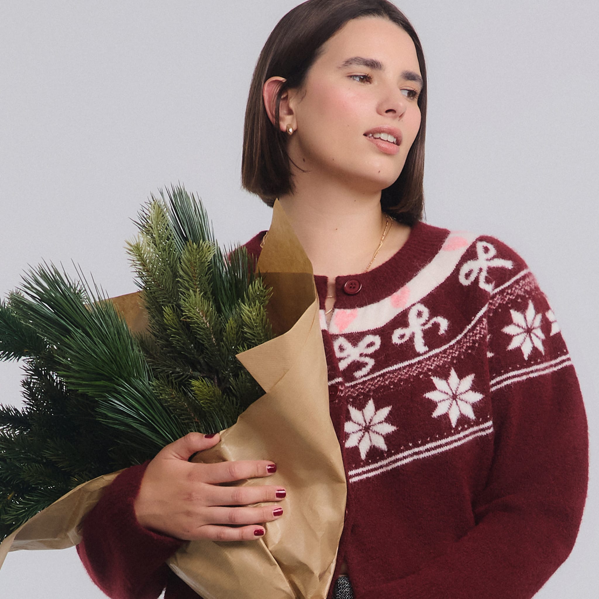 model wearing xmas jumper holding green branches wrapped in brown paper