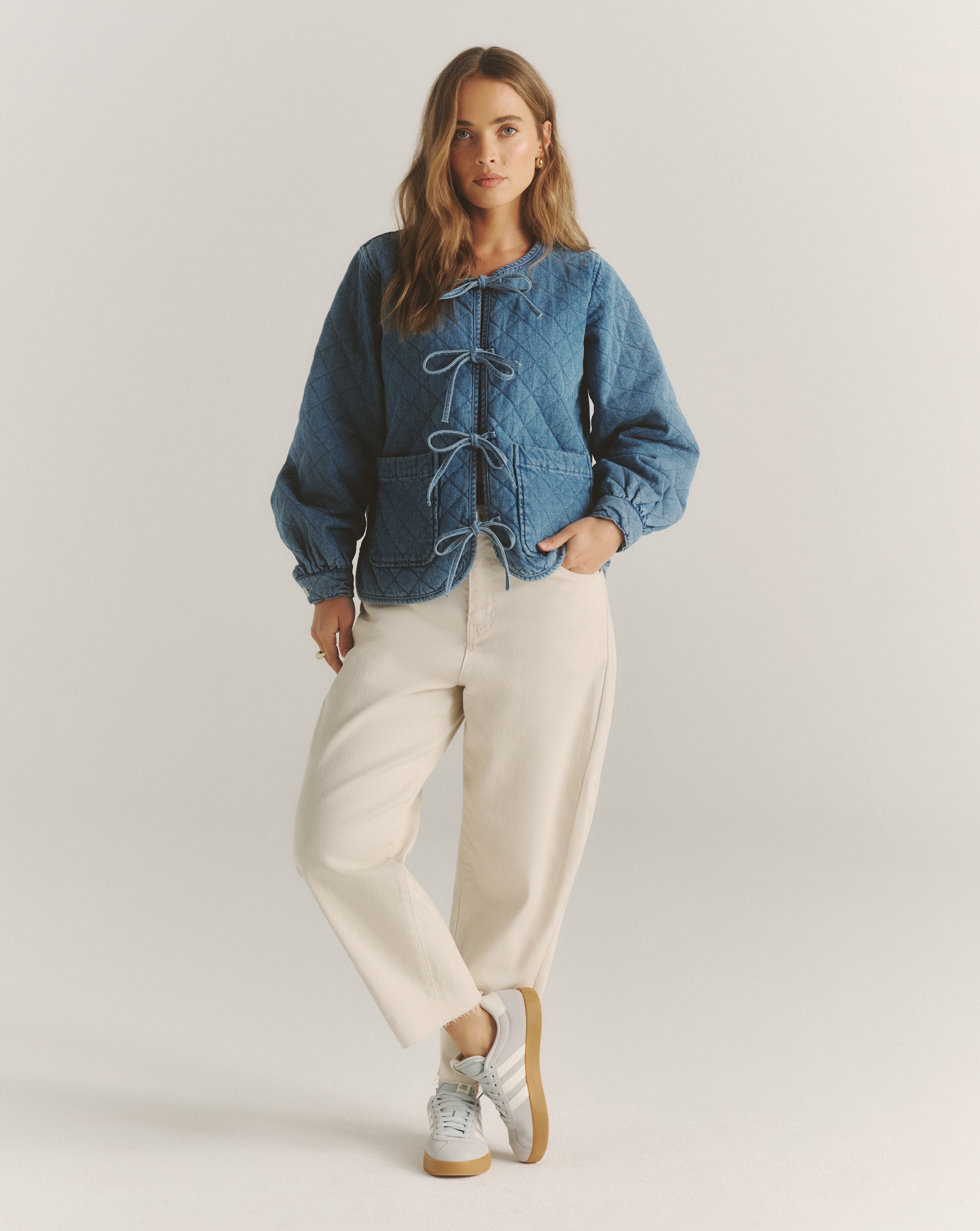 Model wears cropped barrel jeans in off-white
