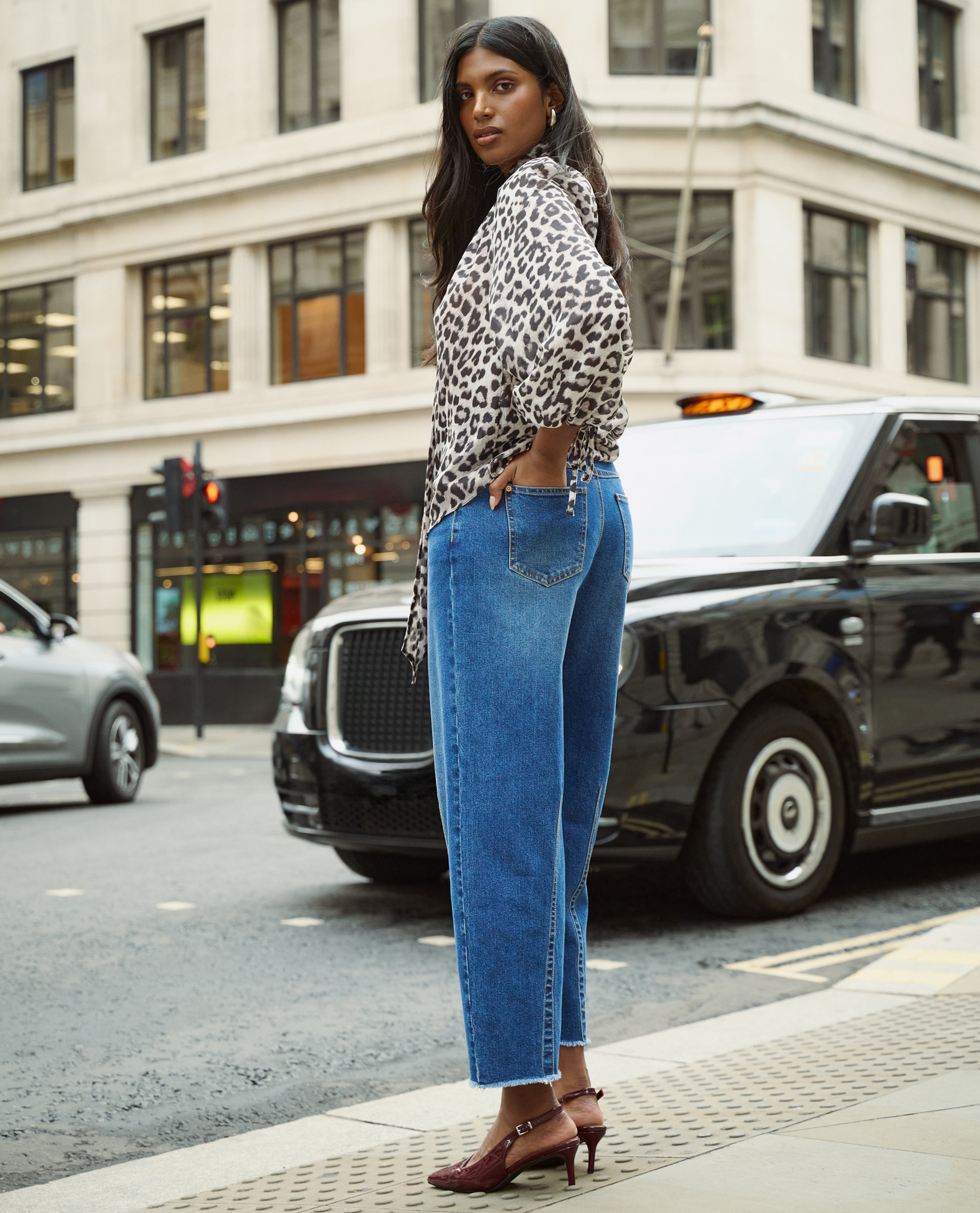 Model wears print top and mid blue jeans