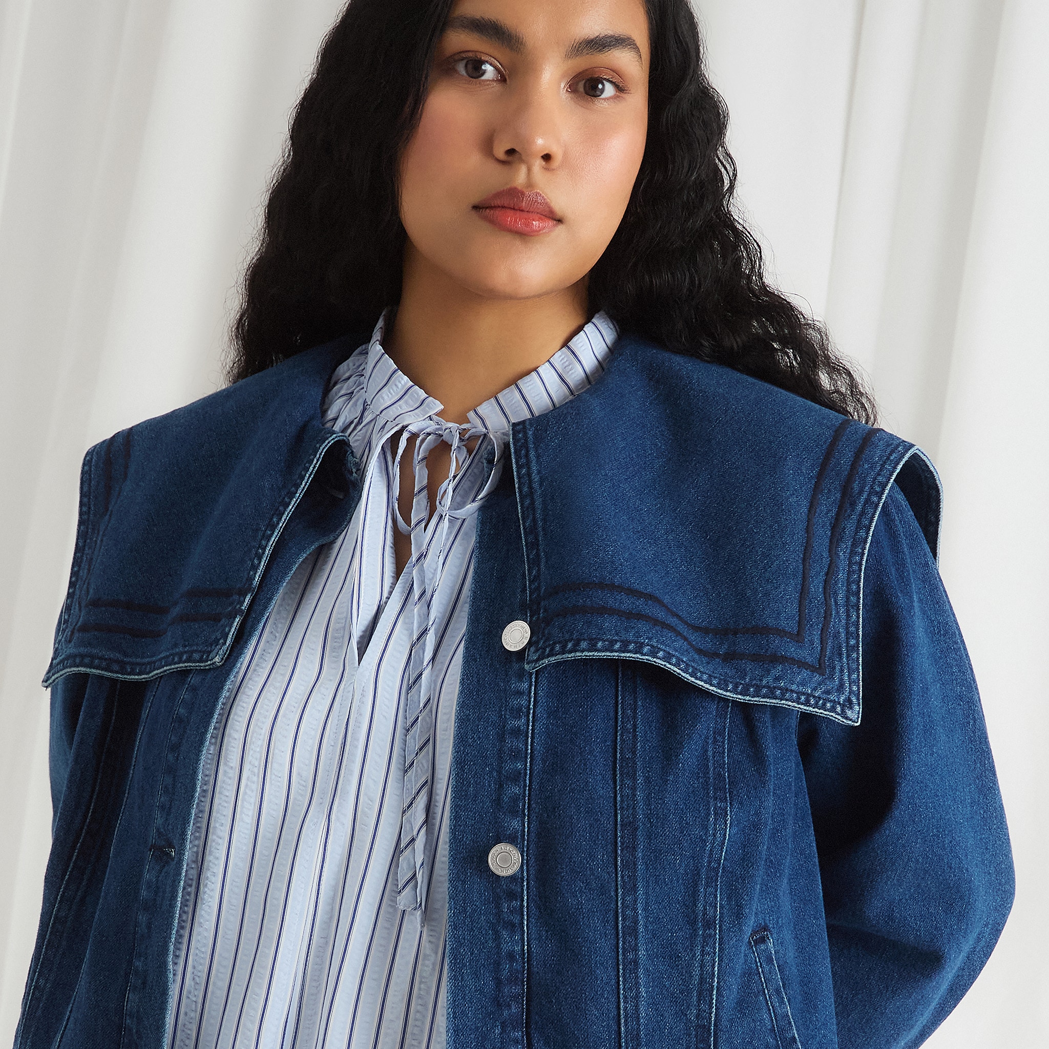 Model wears denim jacket and light blue top