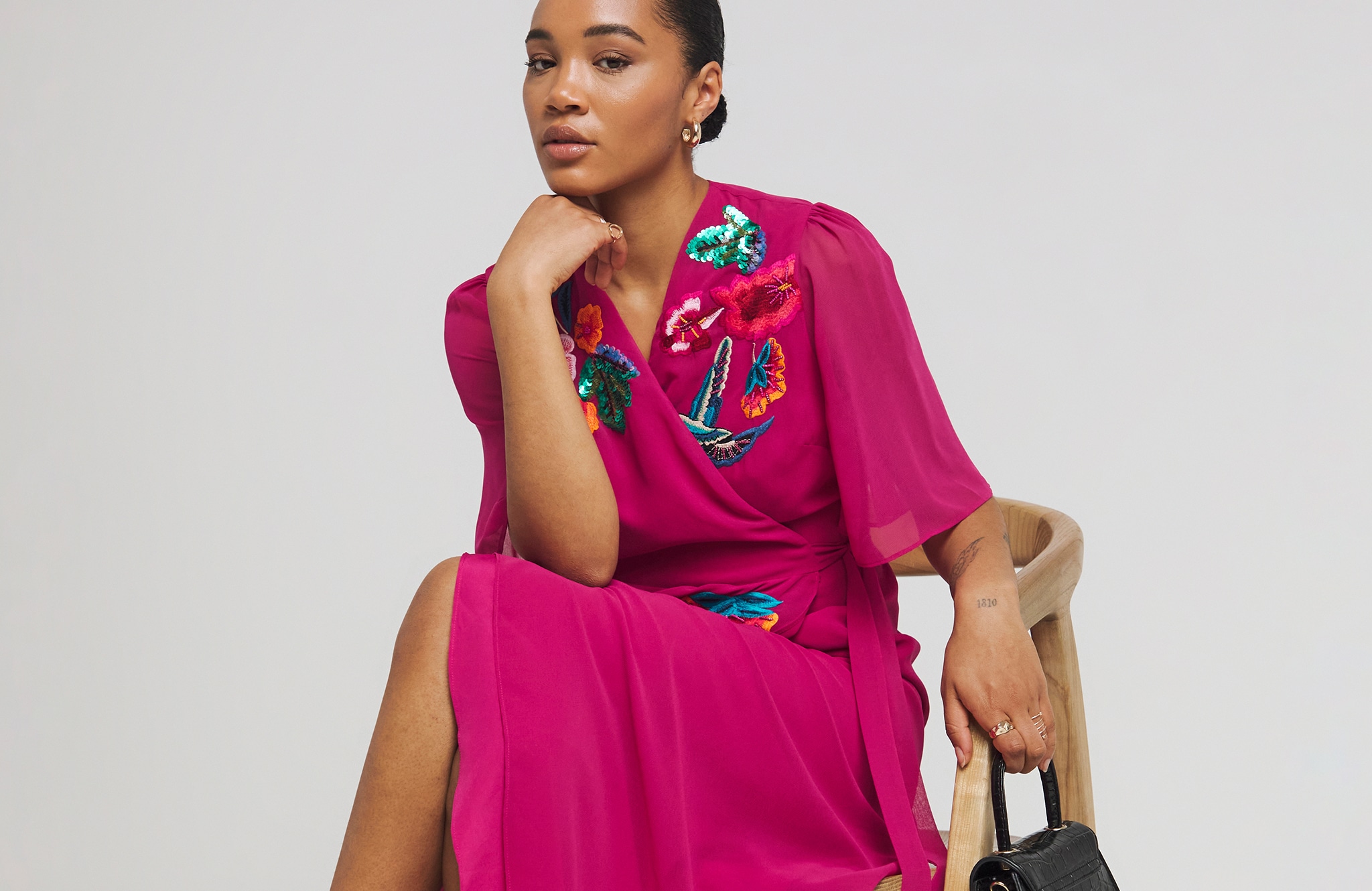 Model is wearing a Hope & Ivy embroidered pink multi-coloured wrap dress