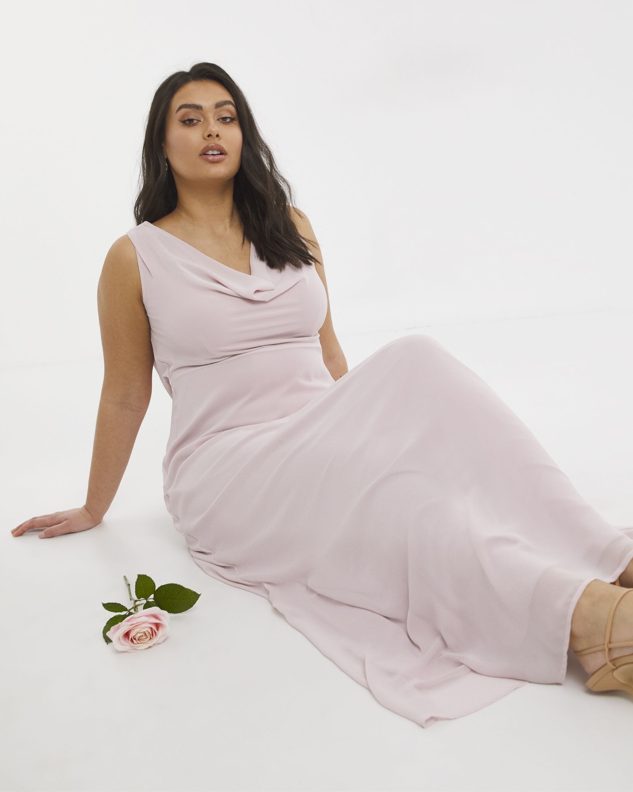 A woman sat on the floor wearing a light pink 3/4 length dress.