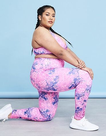 model kneeling wearing pink and purple print leggings