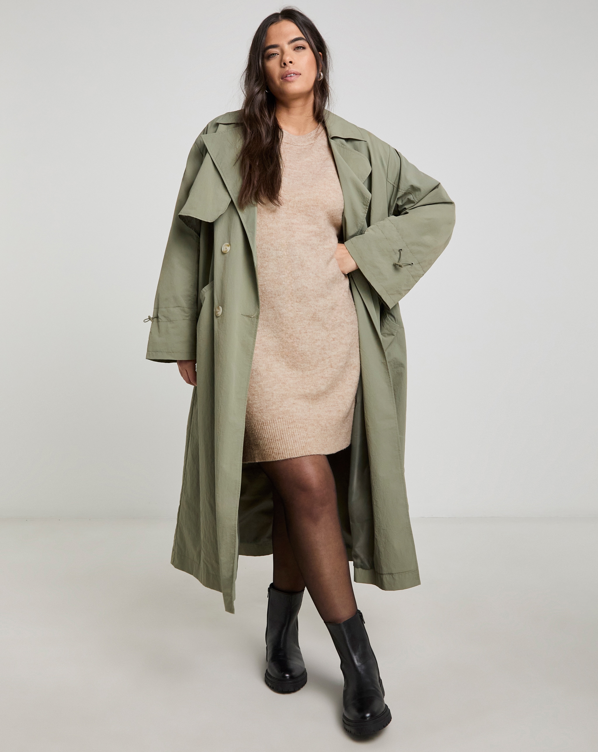 model wearing green long coat and black boots