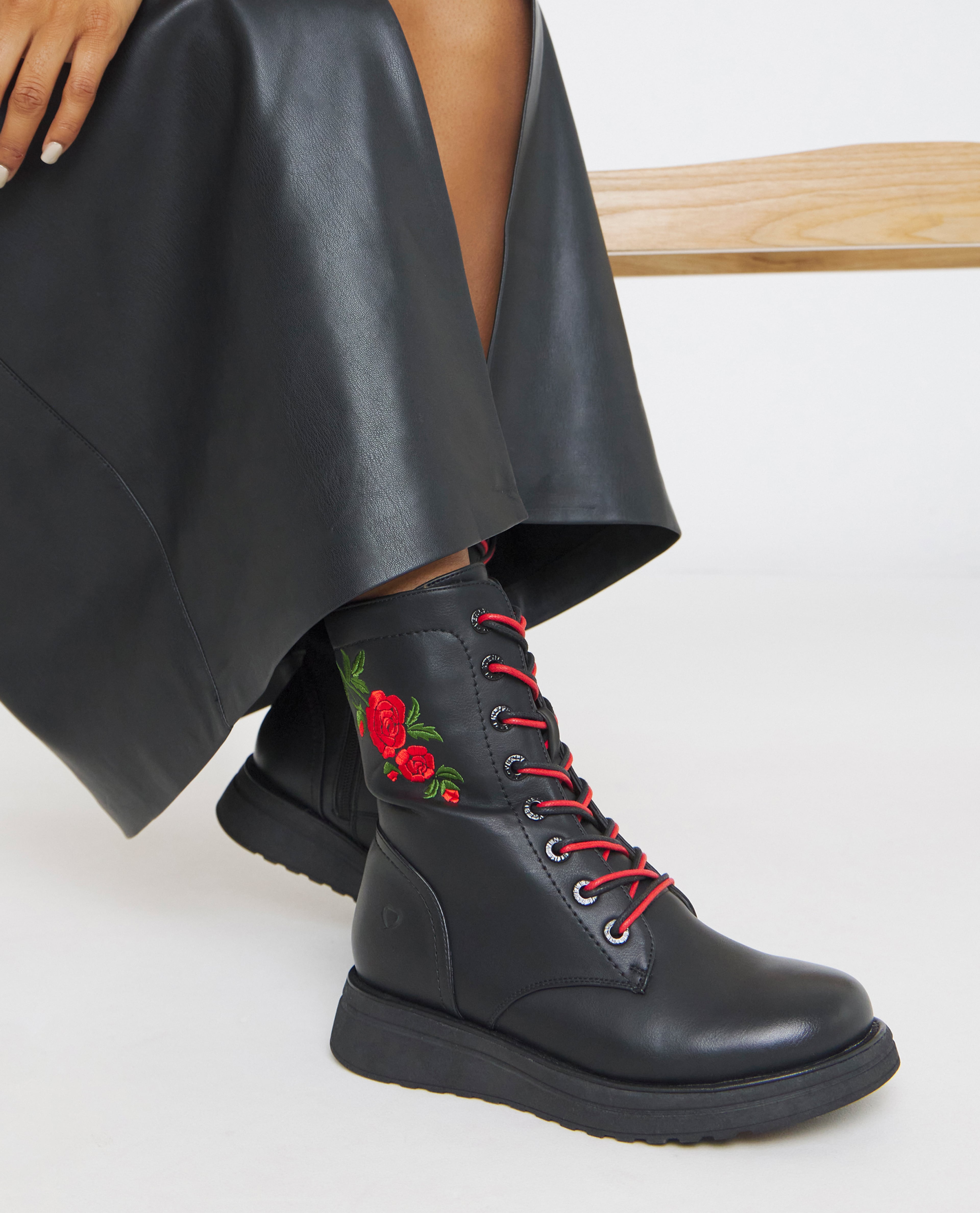 Model wears black boots with embroidery detail